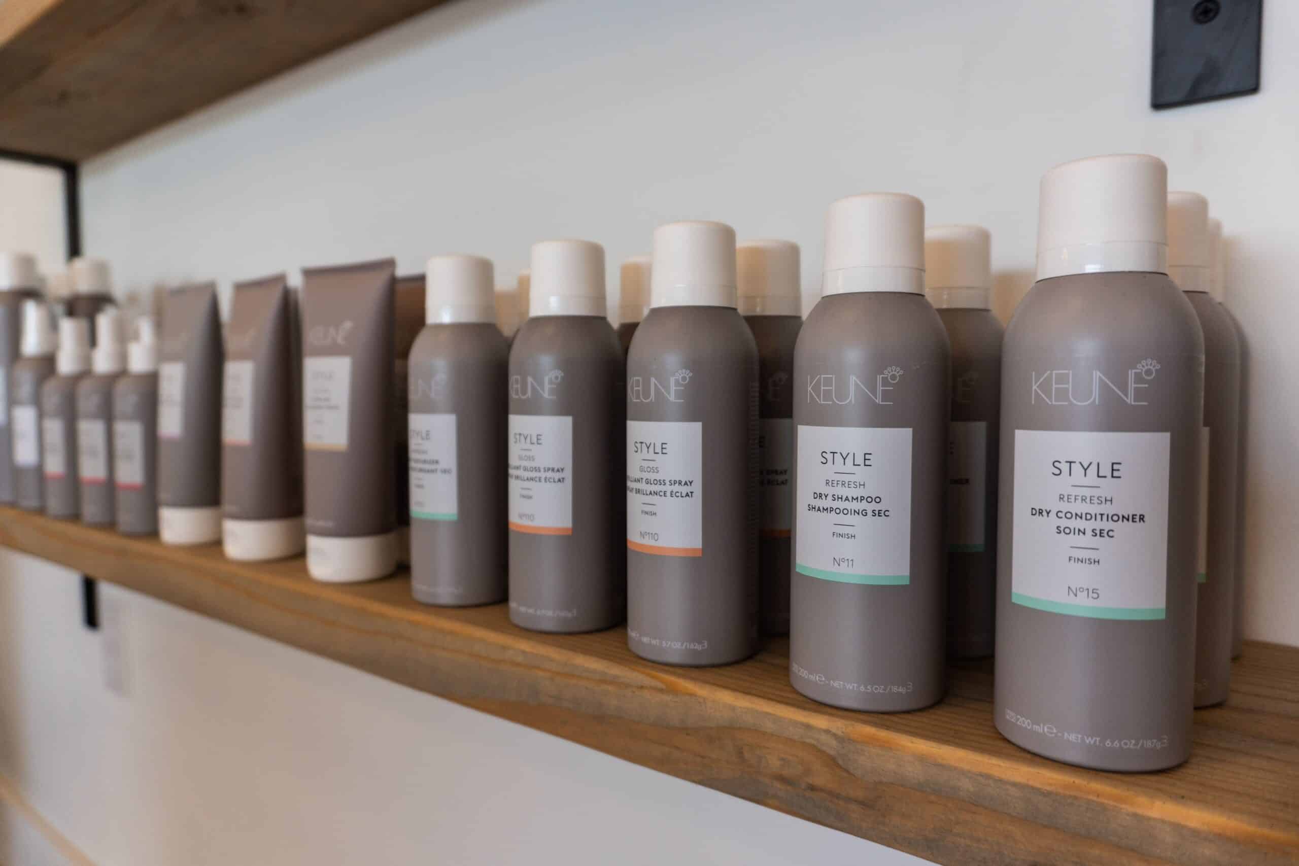 A shelf displays multiple gray and white branded hair product bottles and tubes.
