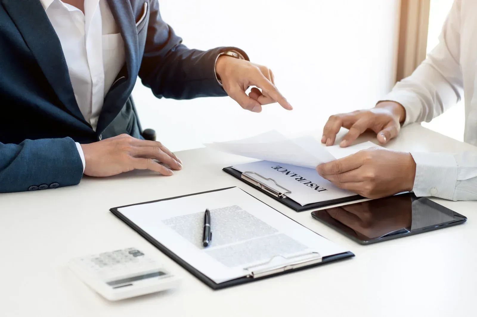 Two people reviewing contract documents at a desk, one pointing.