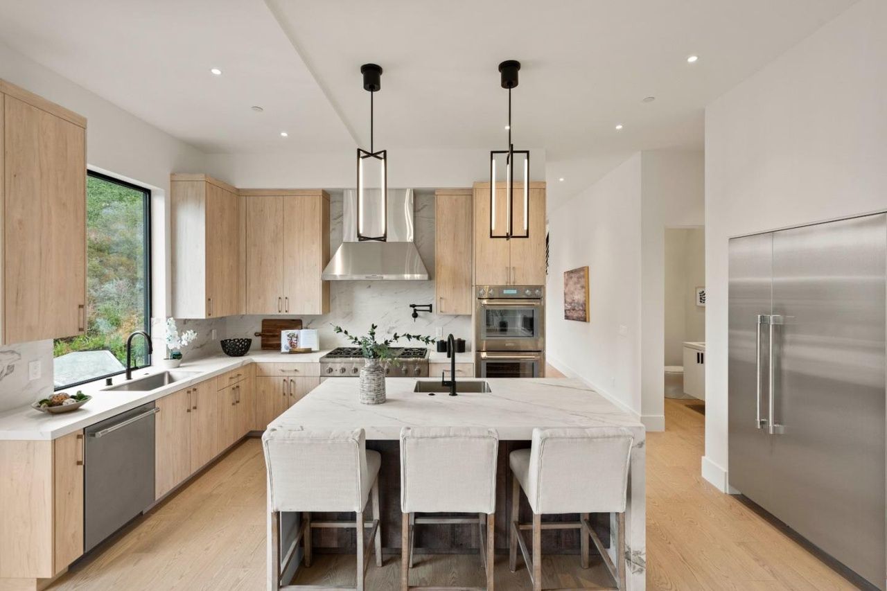 A kitchen with stainless steel appliances , wooden cabinets , and a large island.