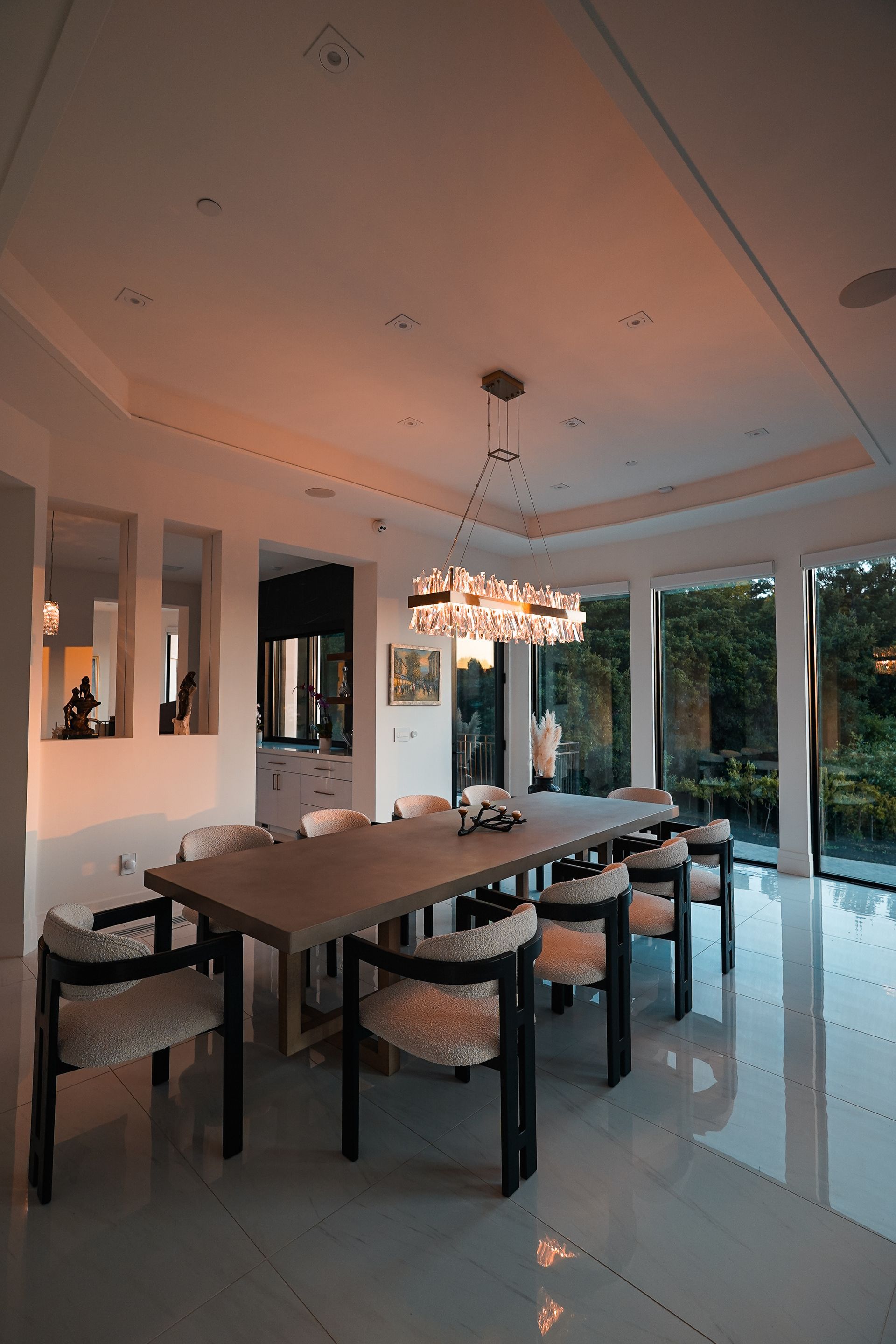 A dining room with a long table and chairs and a chandelier.