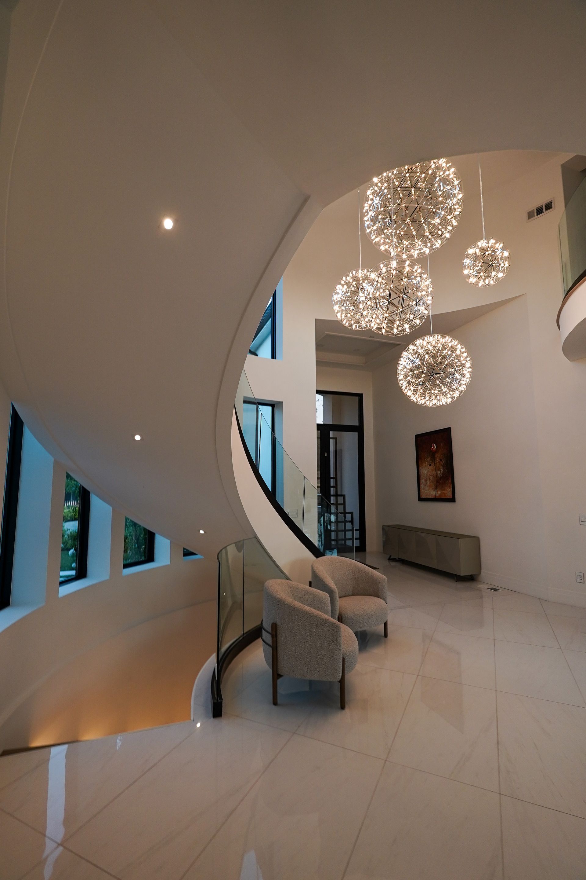 A hallway with a spiral staircase and a chandelier hanging from the ceiling