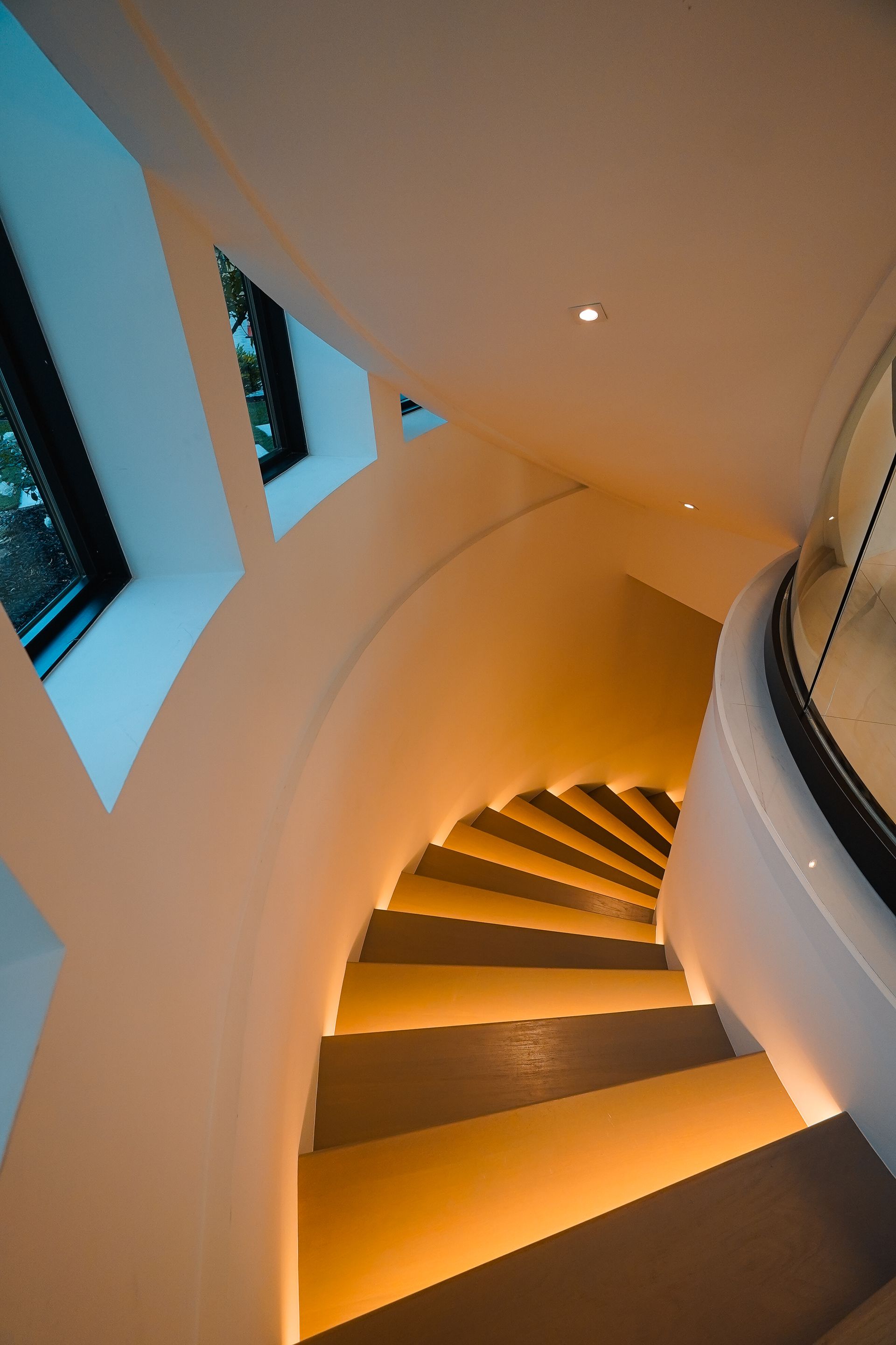 Looking up at a spiral staircase with lights on the steps