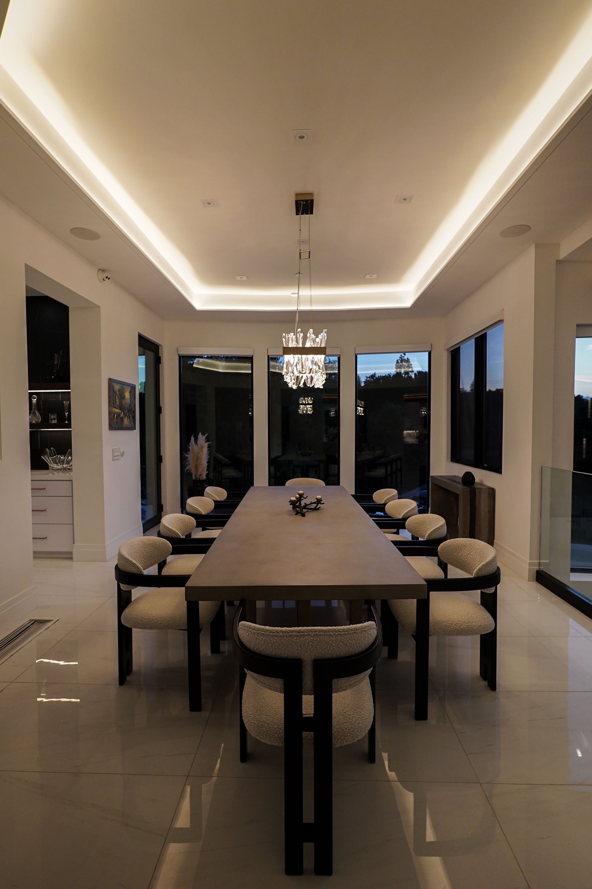 A dining room with a long table and chairs and a chandelier.