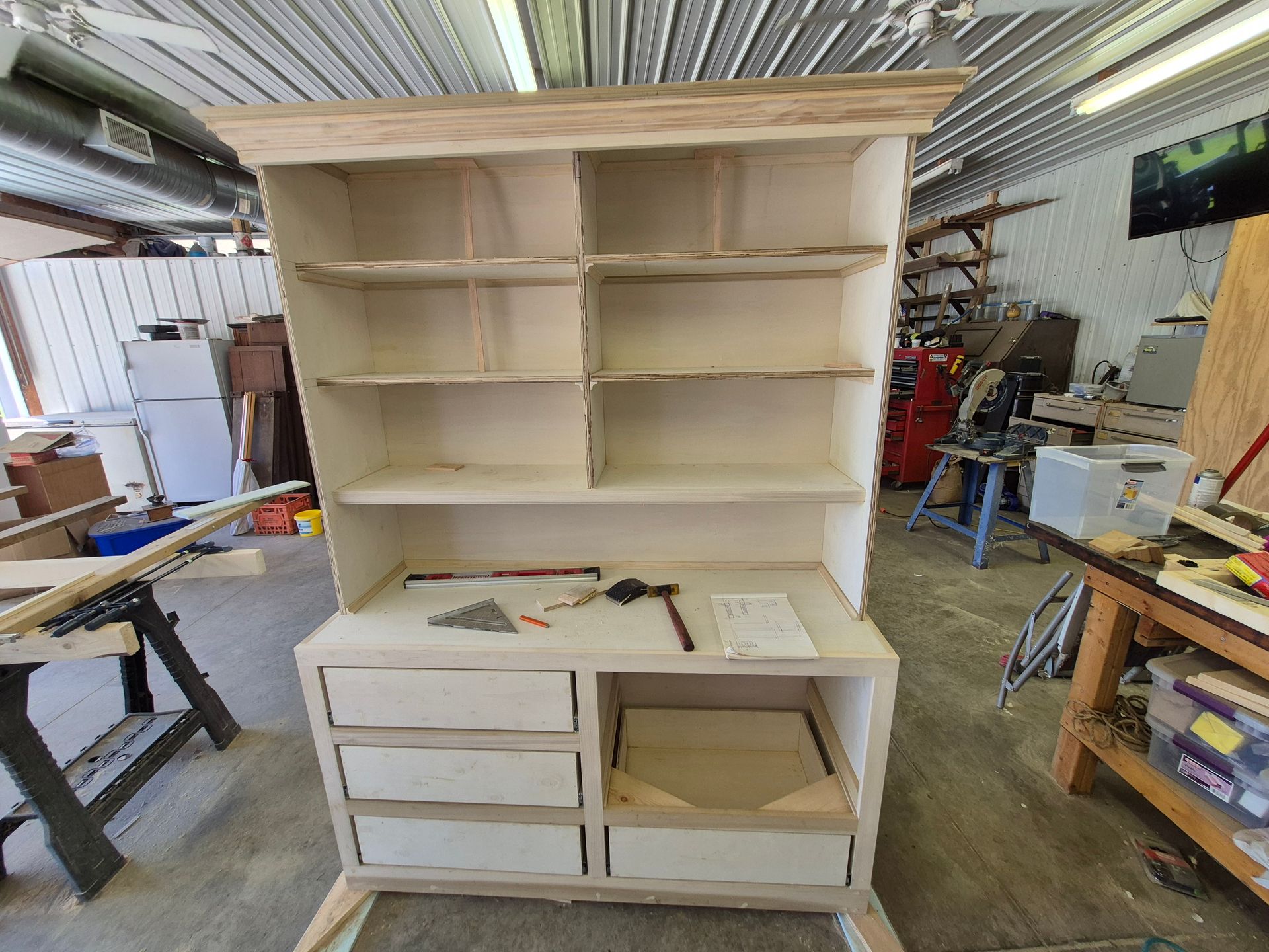 White wooden shelving unit with drawers in a workshop, under construction