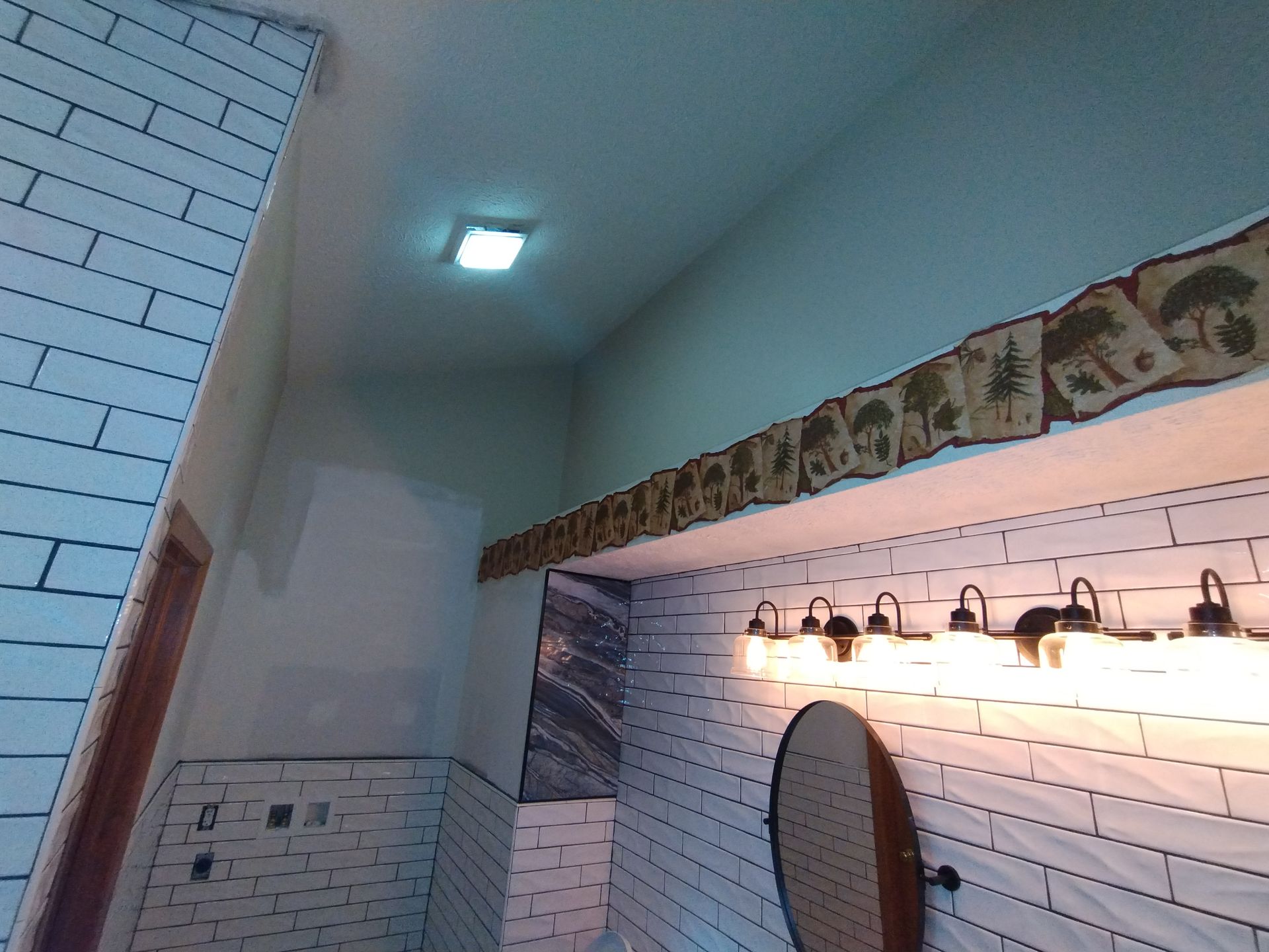 Bathroom with brick tile, a light fixture, and a decorative border.
