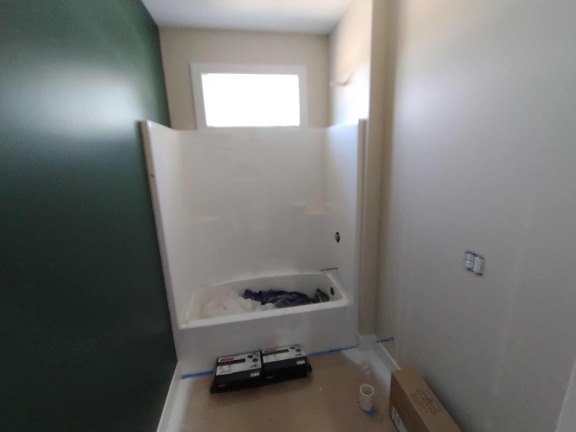 Bathroom with white shower stall, dark green and light walls.