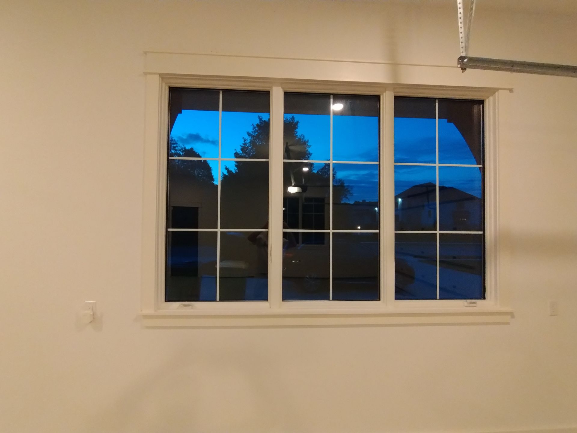 Window with white frame reflecting a blue sky and a building.
