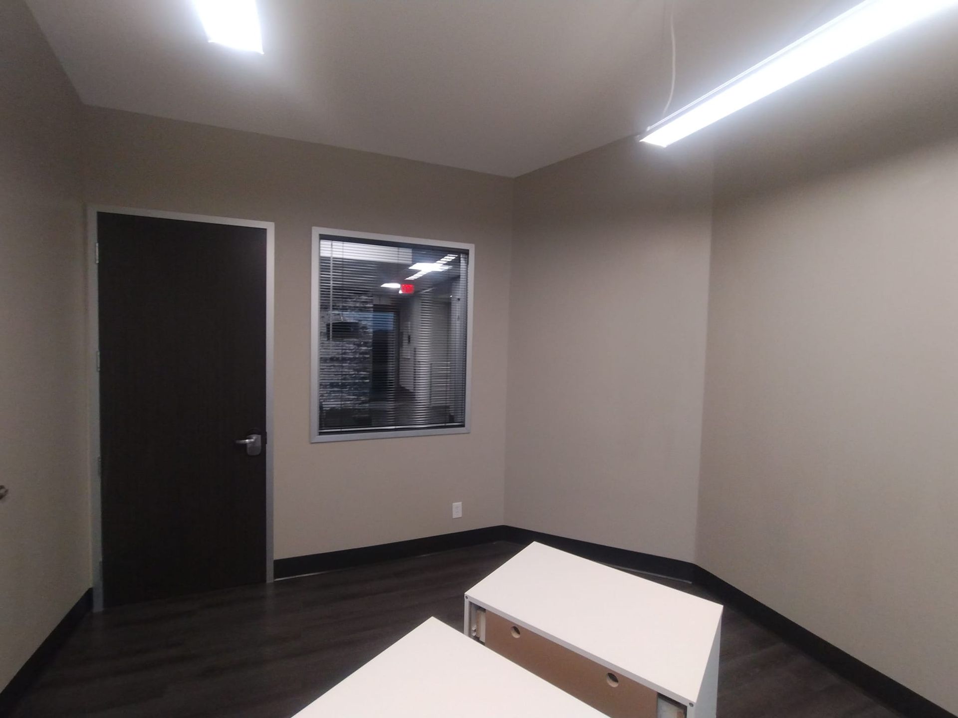 An empty room with two desks and a window