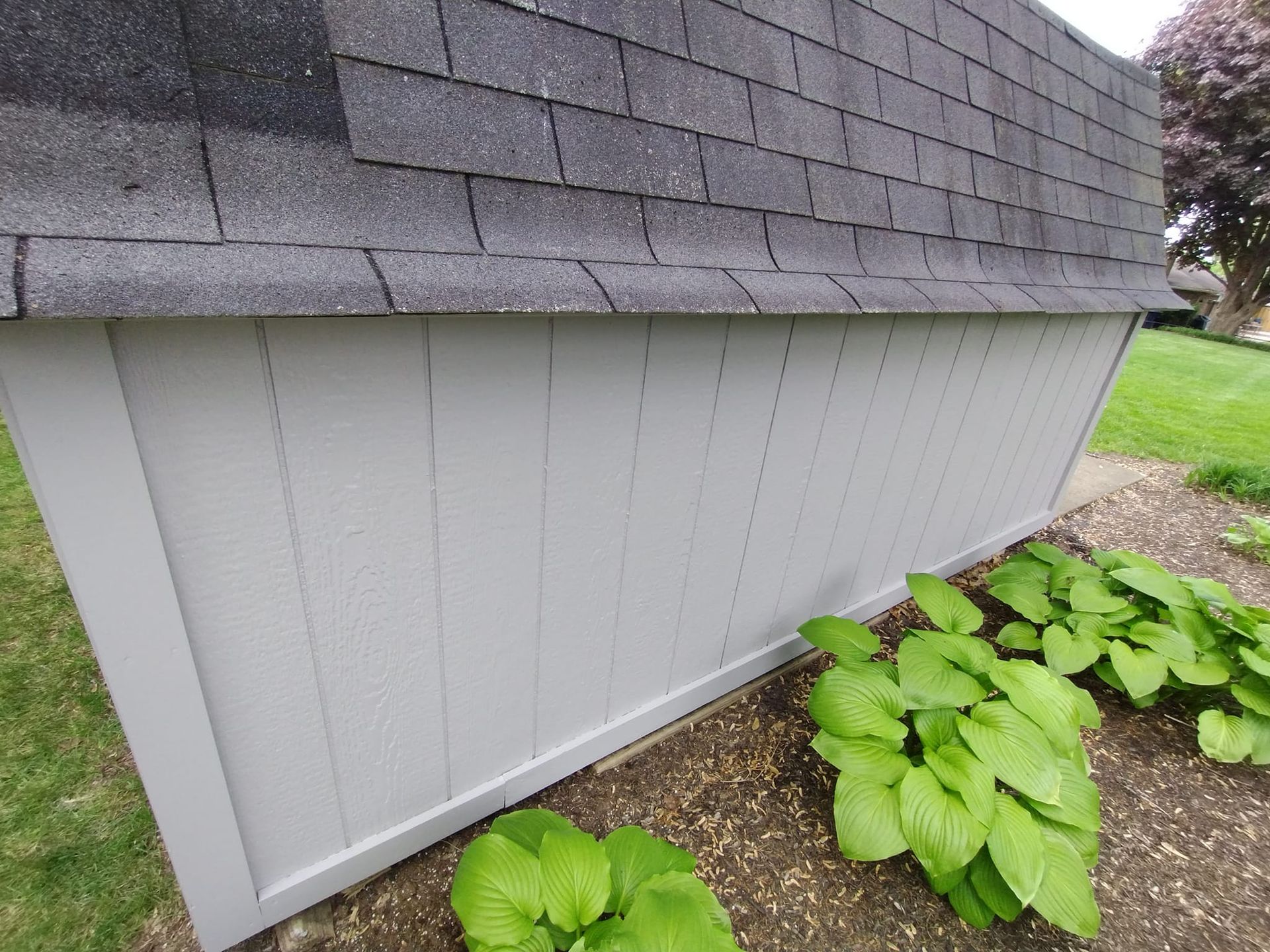 A white fence is sitting next to a roof in a yard.