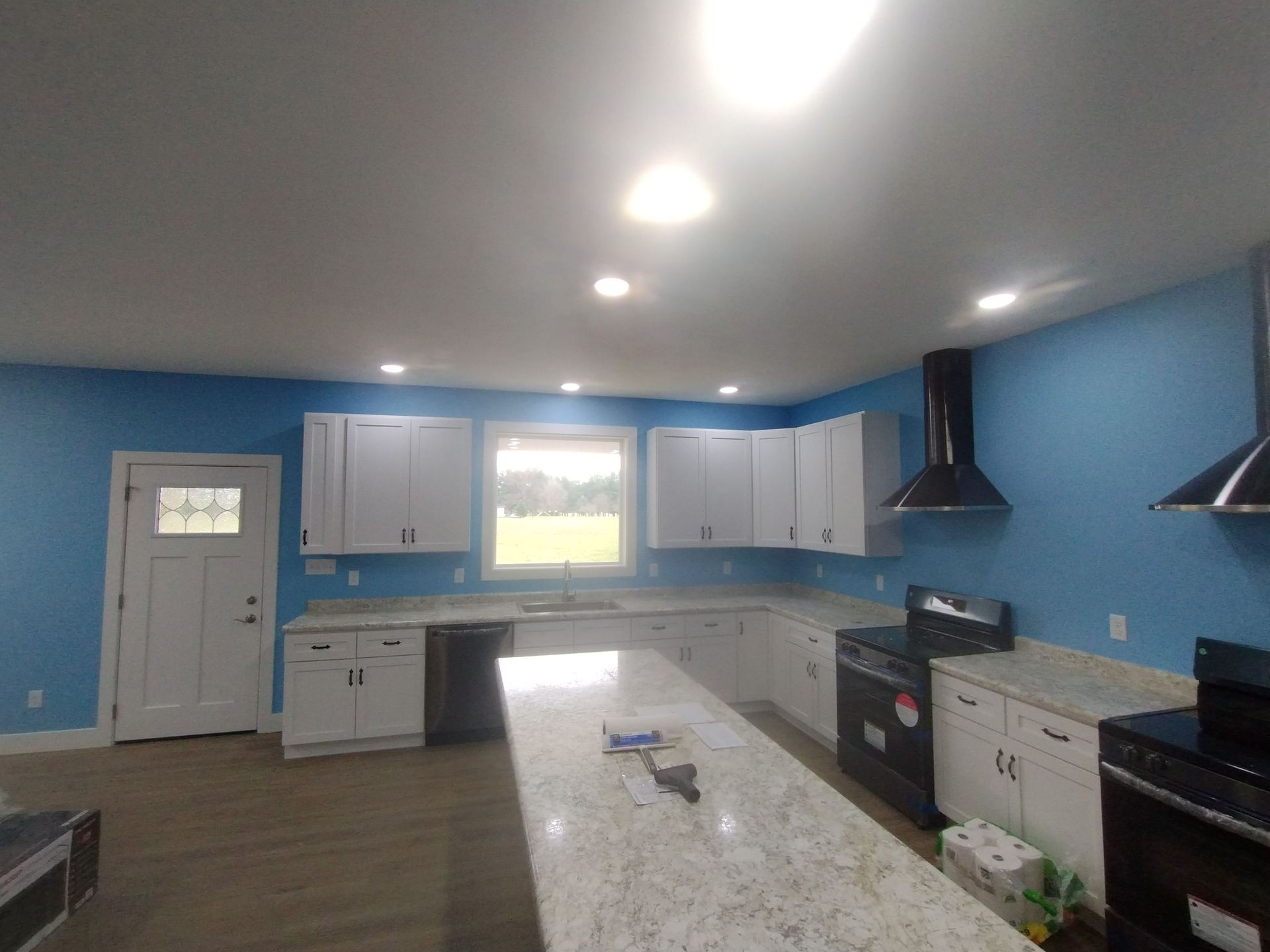 A kitchen with blue walls and white cabinets
