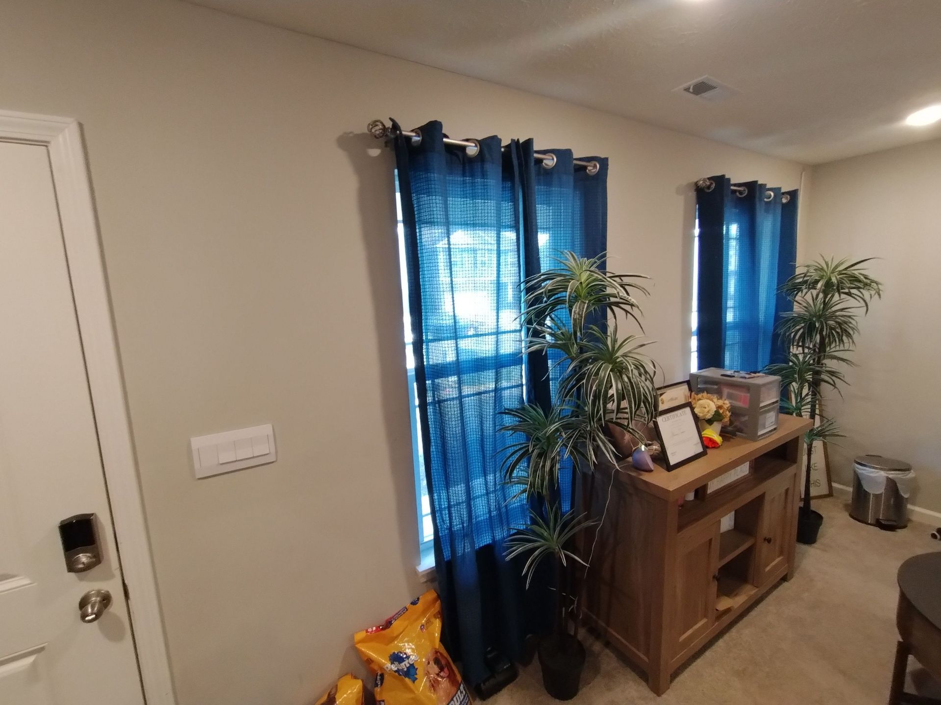 A living room with blue curtains and a wooden dresser.