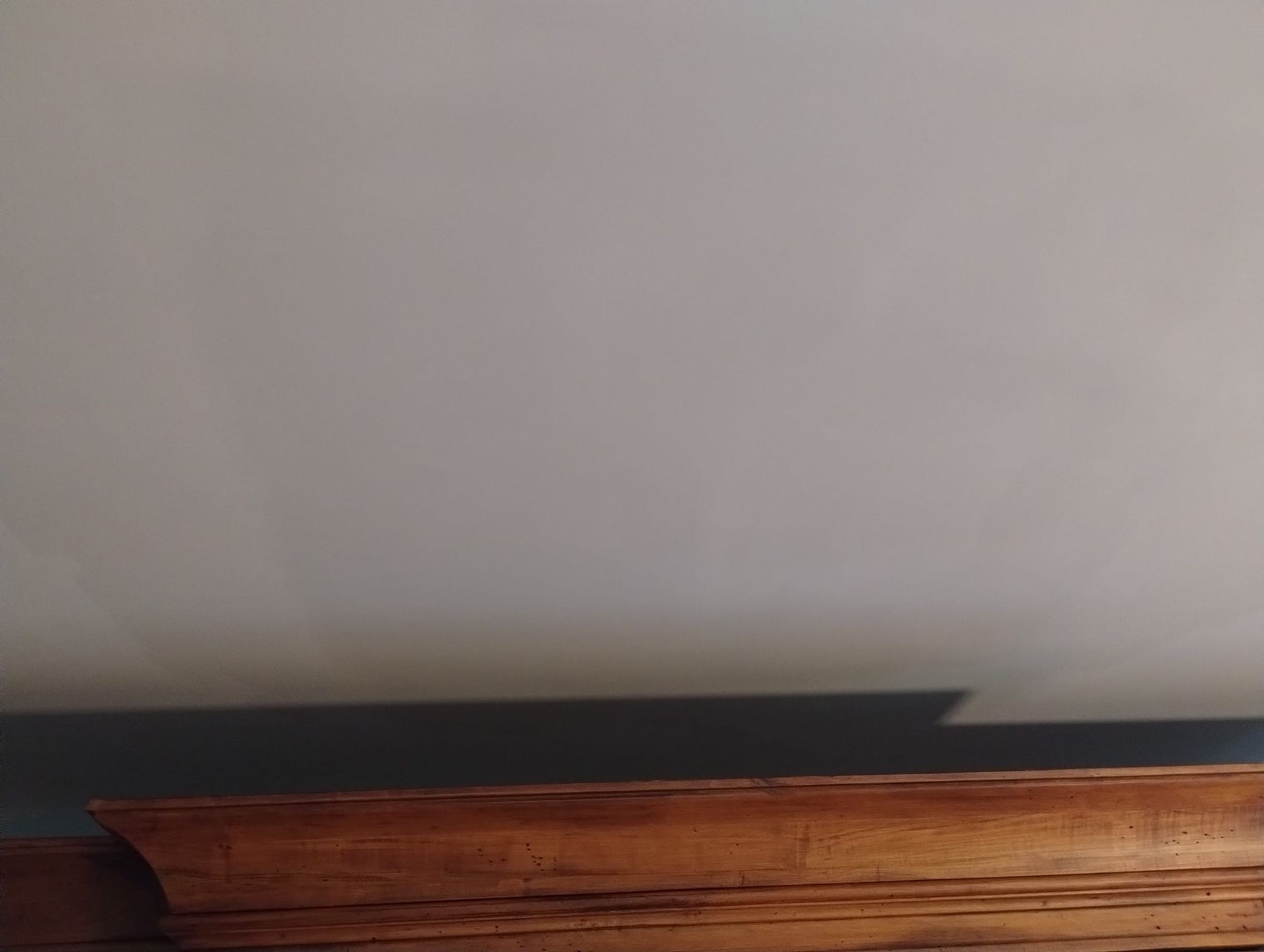 A white wall with a wooden trim and a shadow on it.