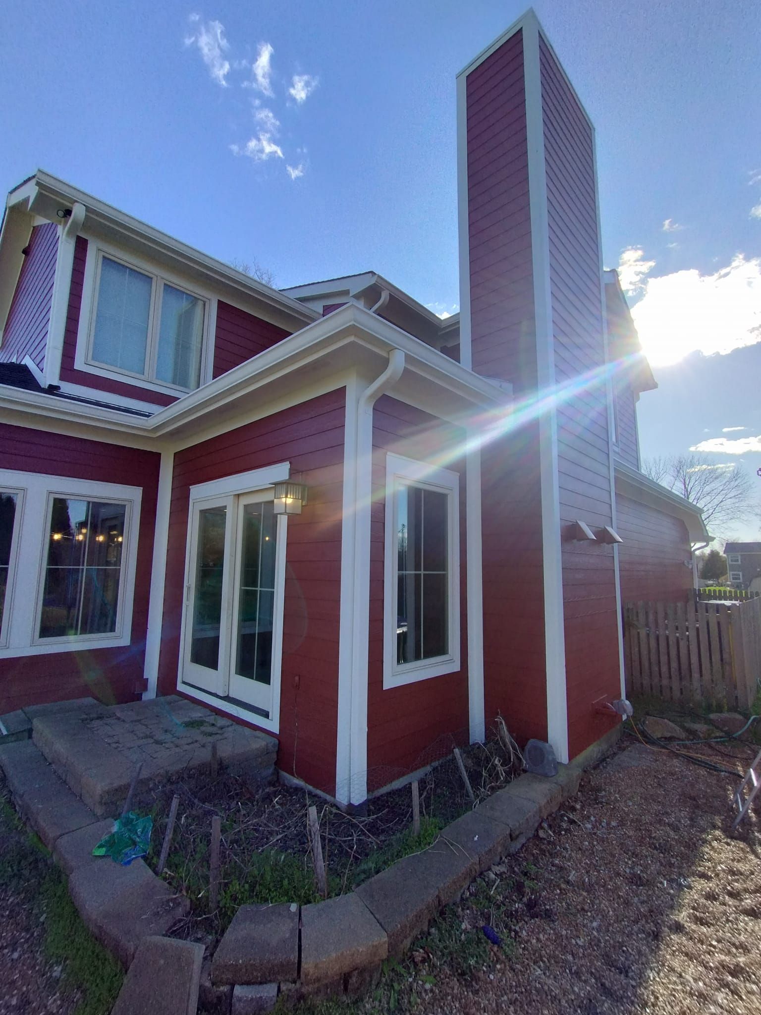 Red house exterior with white trim, tall chimney, and sunny sky.
