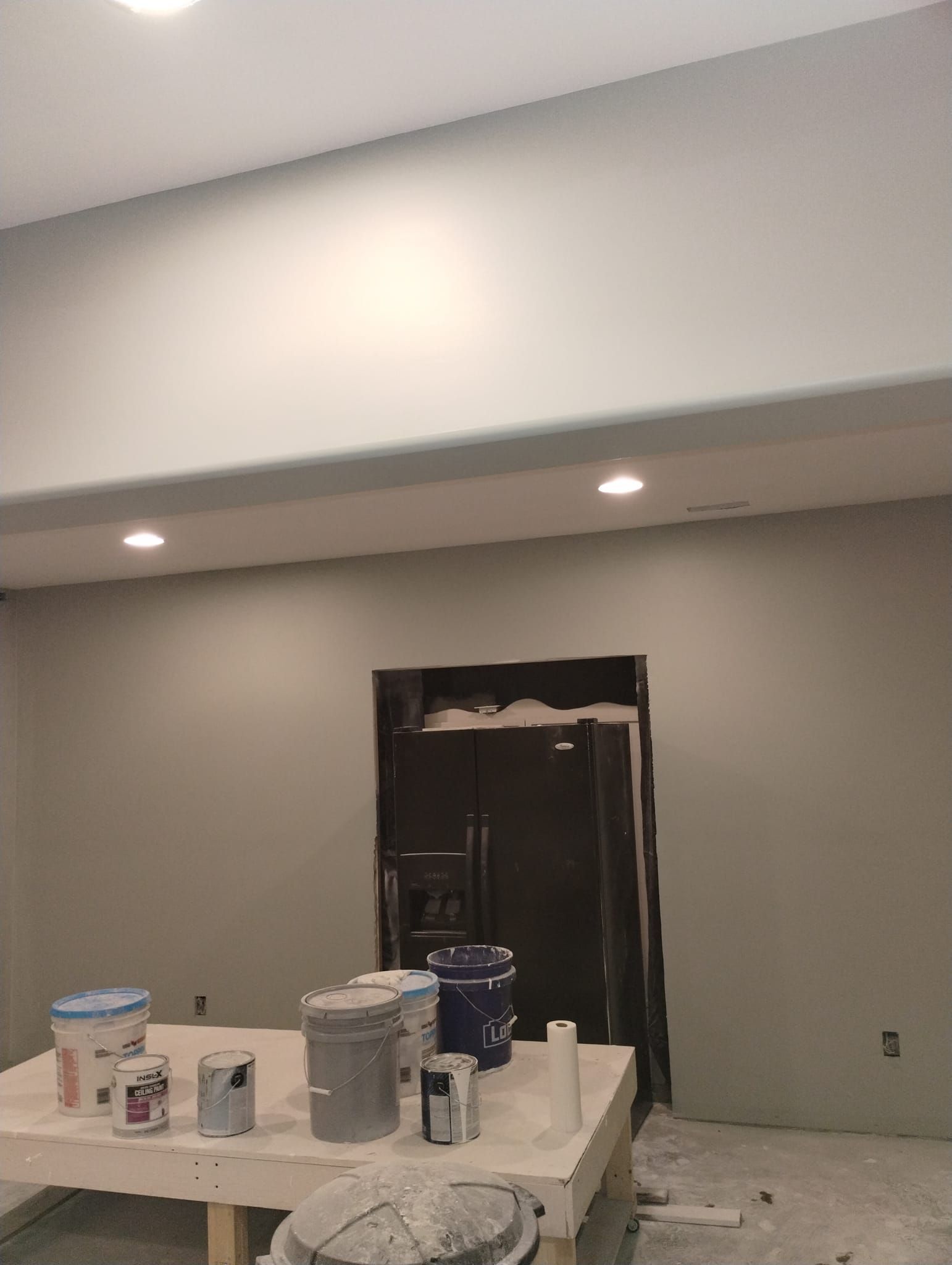 A room with a table and buckets of paint on it.
