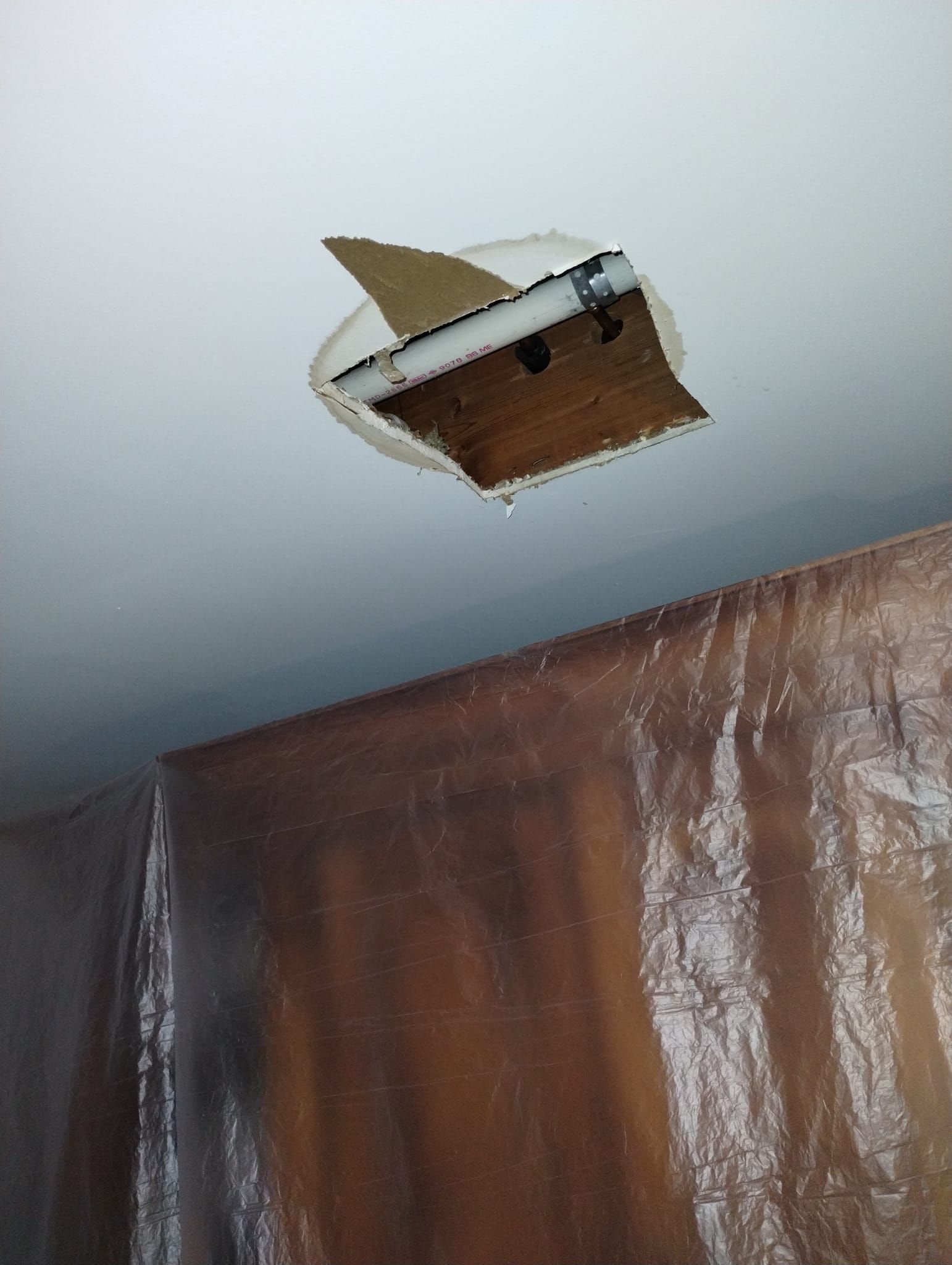 A hole in the ceiling with a piece of cardboard sticking out of it.