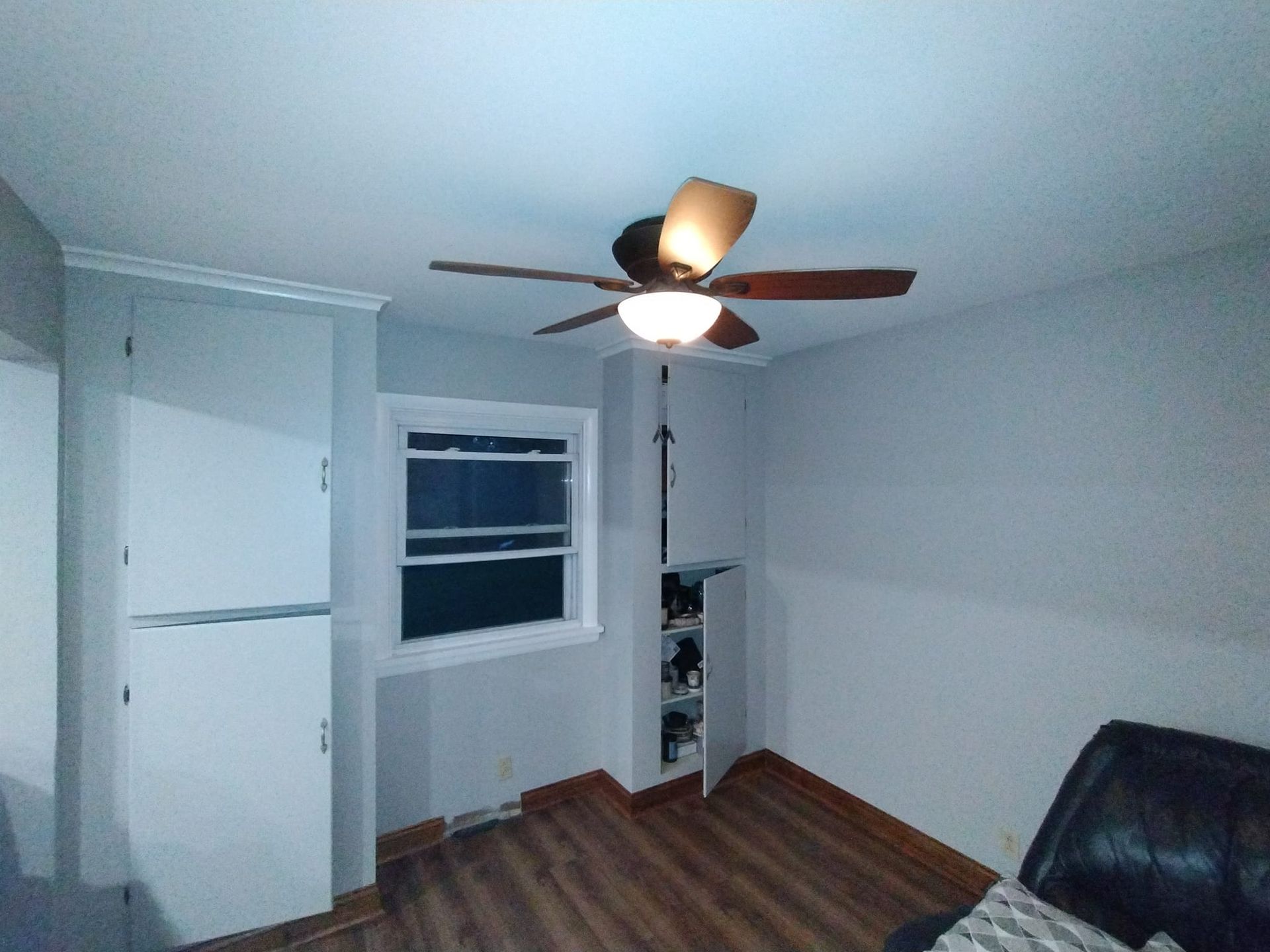 A living room with a ceiling fan and a window.