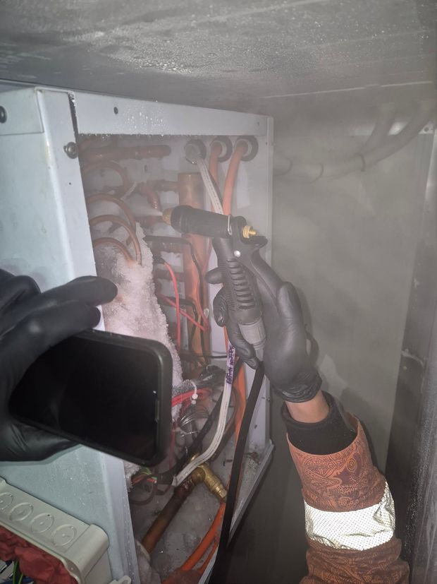 Technician connecting refrigerant lines on an outdoor compressor unit