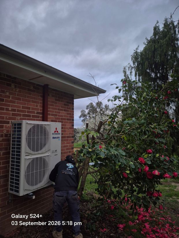 Technician connecting refrigerant lines on an outdoor compressor unit