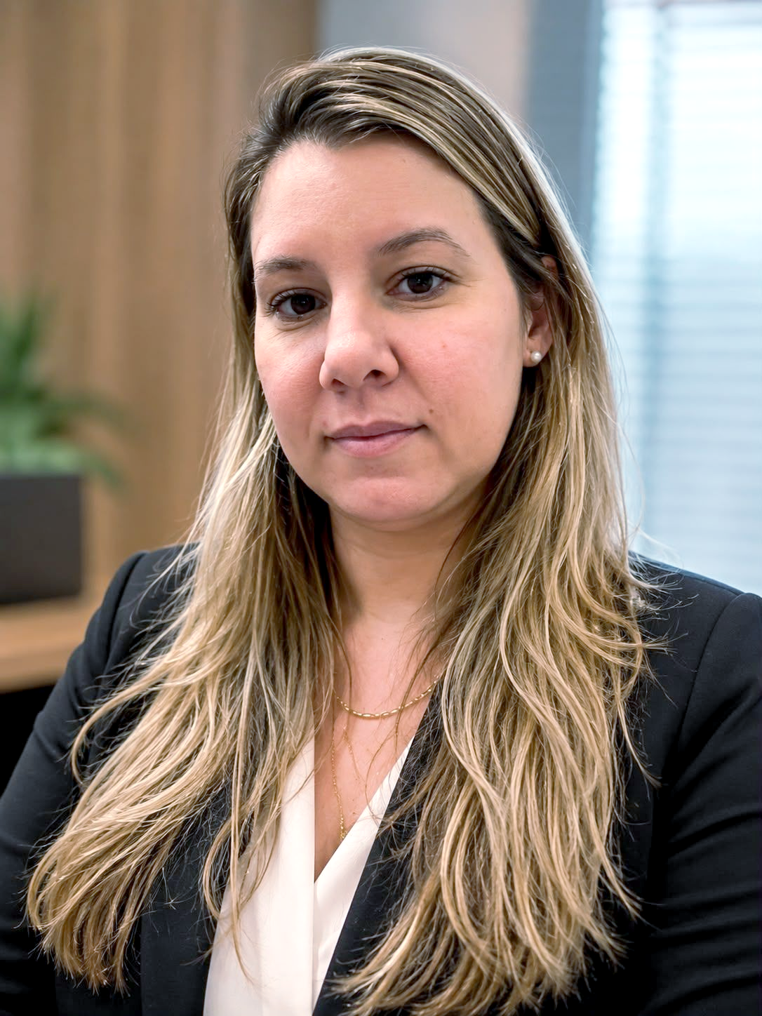 Mulher de blazer, com longos cabelos escuros e usando brincos de argola.