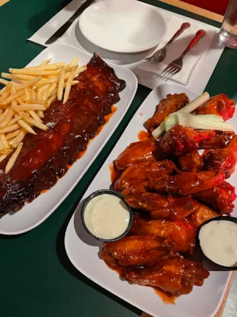 a dish of ribs and fries and a dish of Buffalo chicken wings