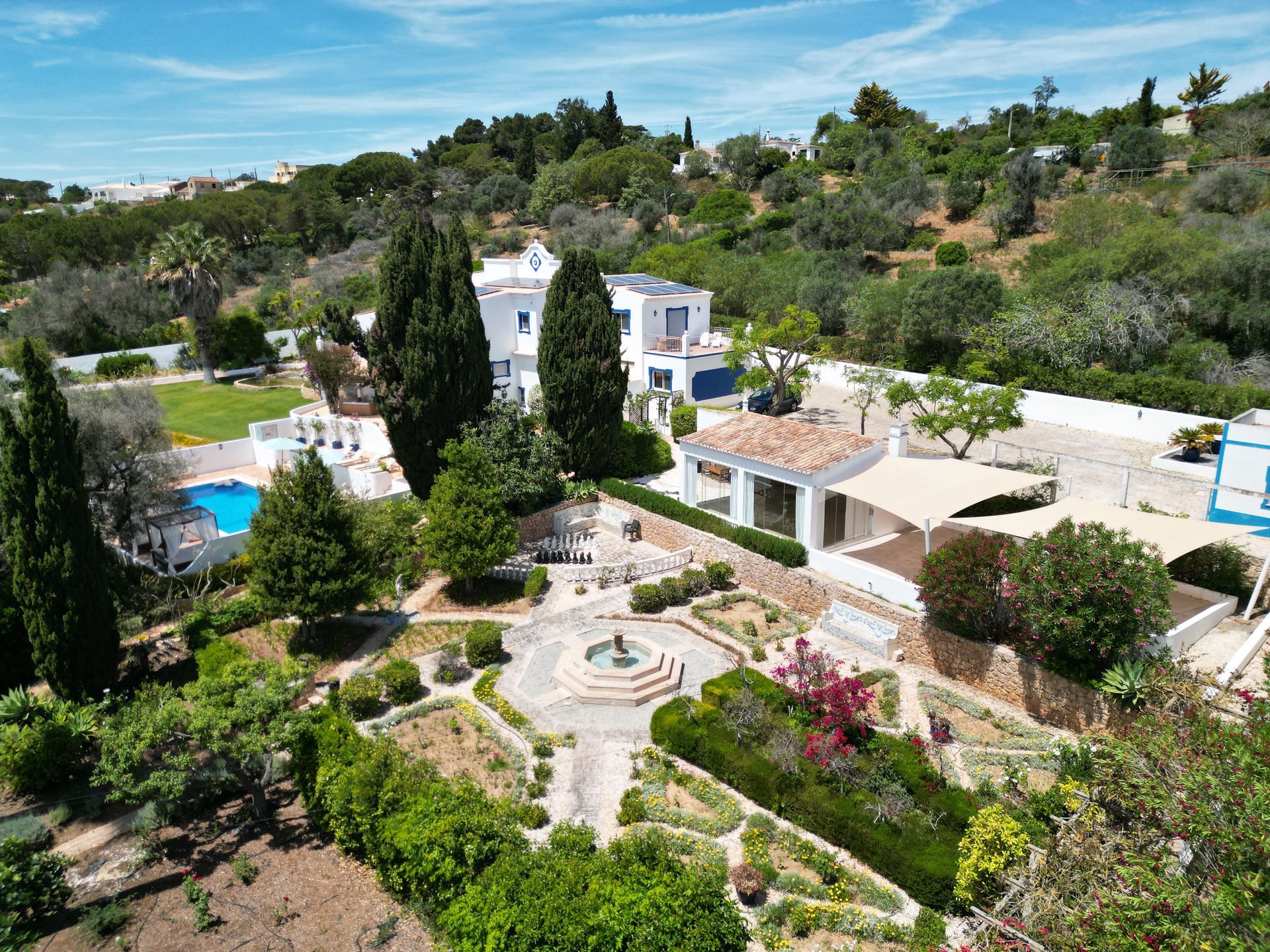 An aerial view of a large white house surrounded by trees and bushes.