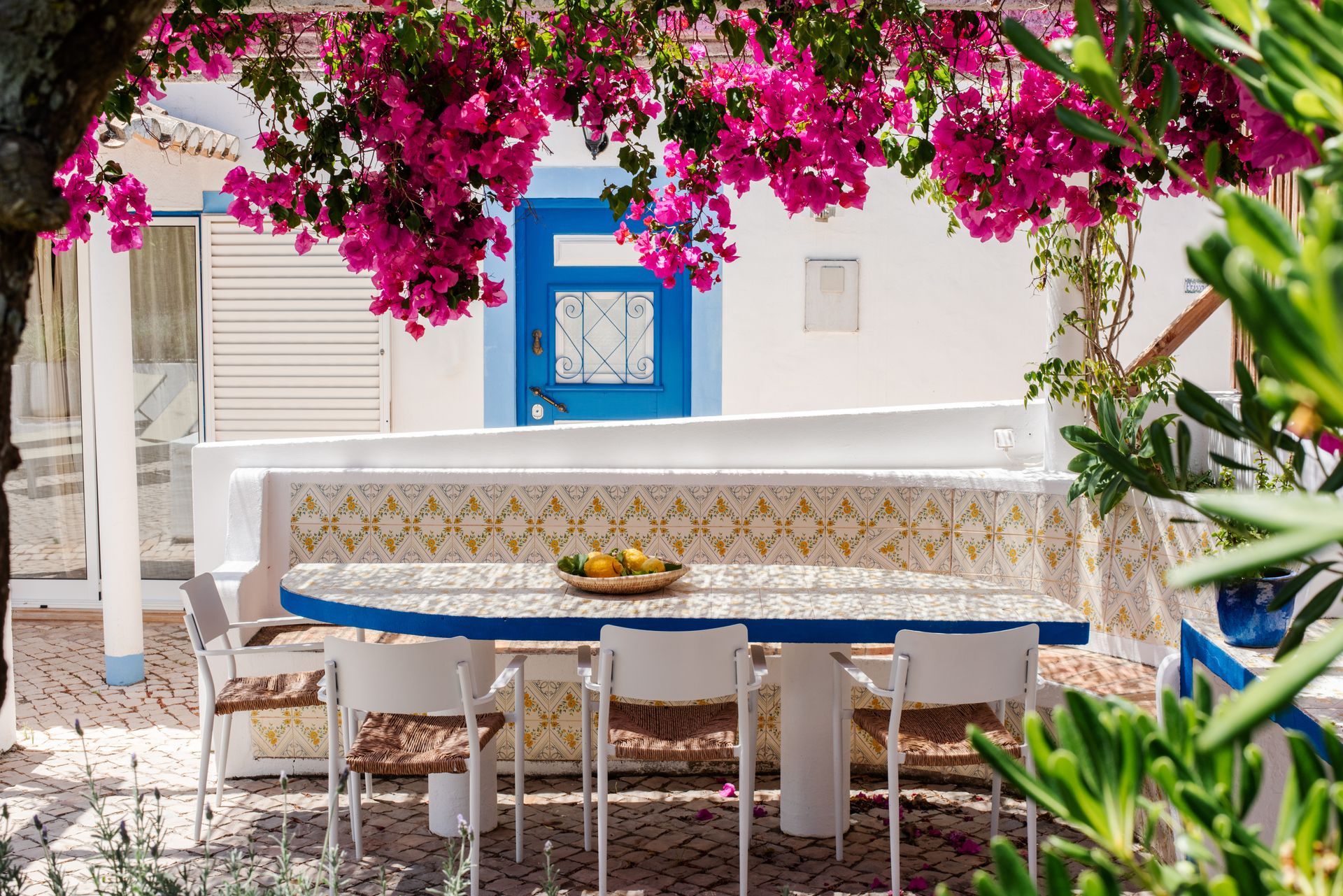 A patio with a table and chairs under a tree with pink flowers.