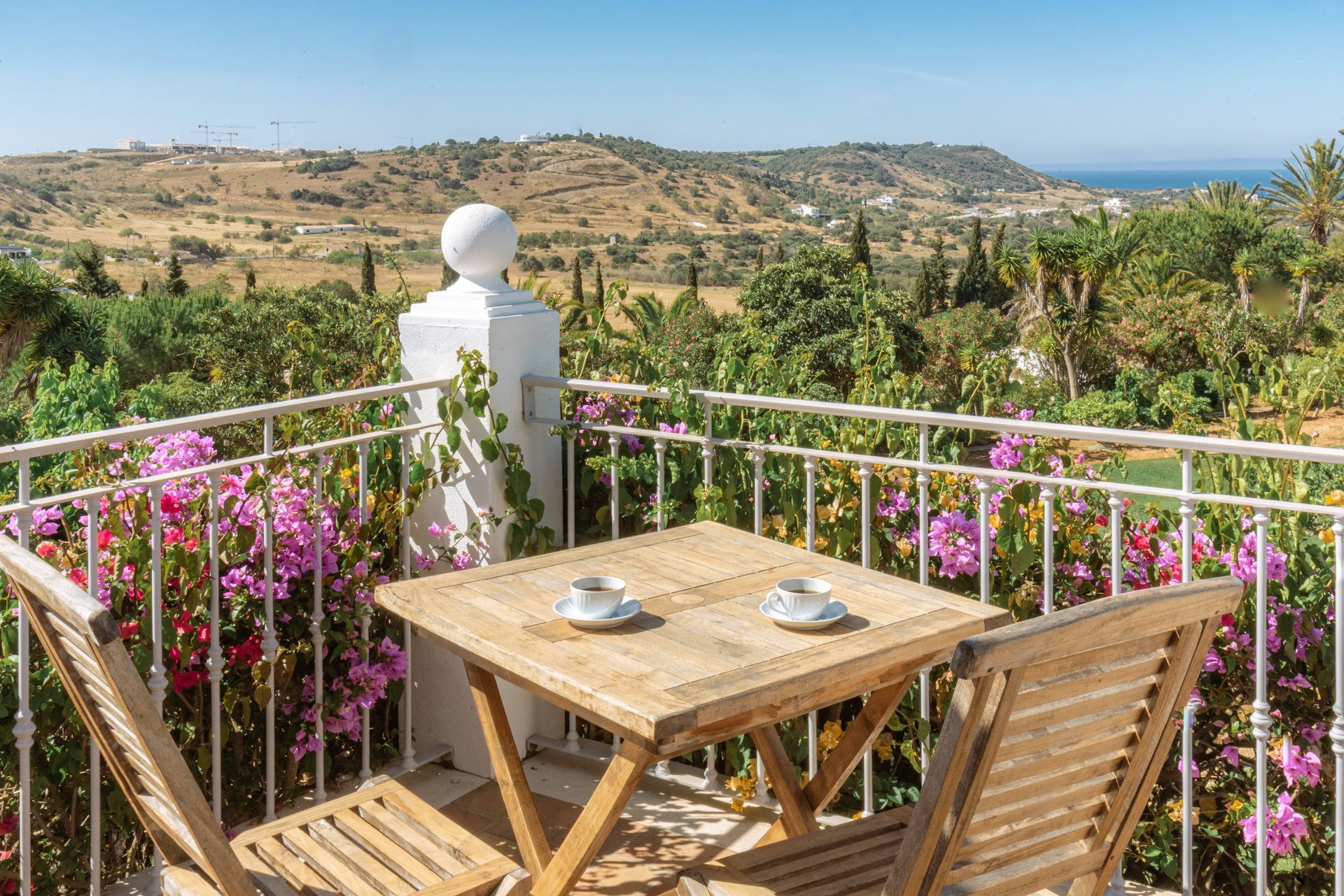 There is a table and chairs on the balcony with a view of the ocean.