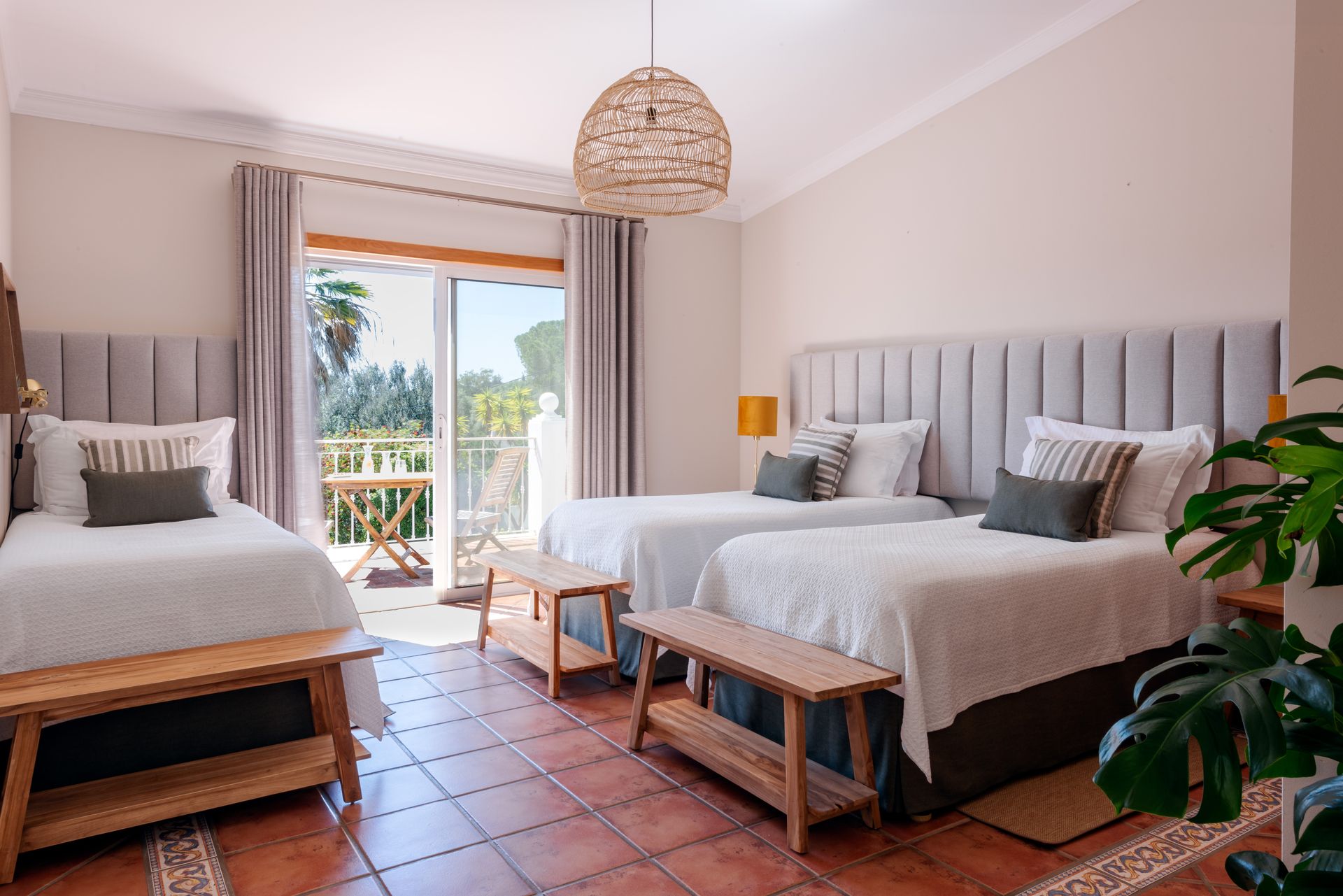 A hotel room with three beds and a sliding glass door.
