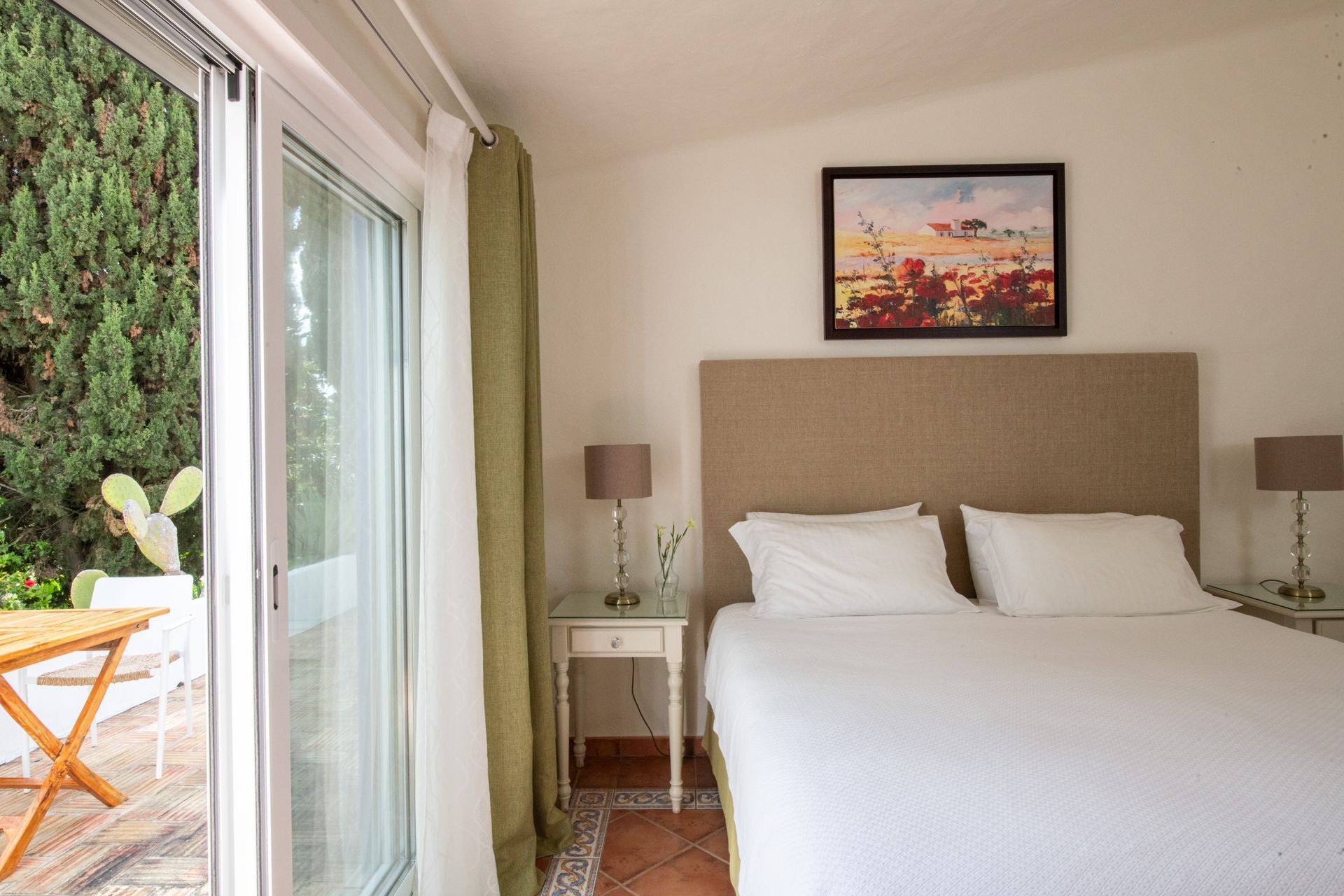 A bedroom with a large bed and a sliding glass door leading to a patio.