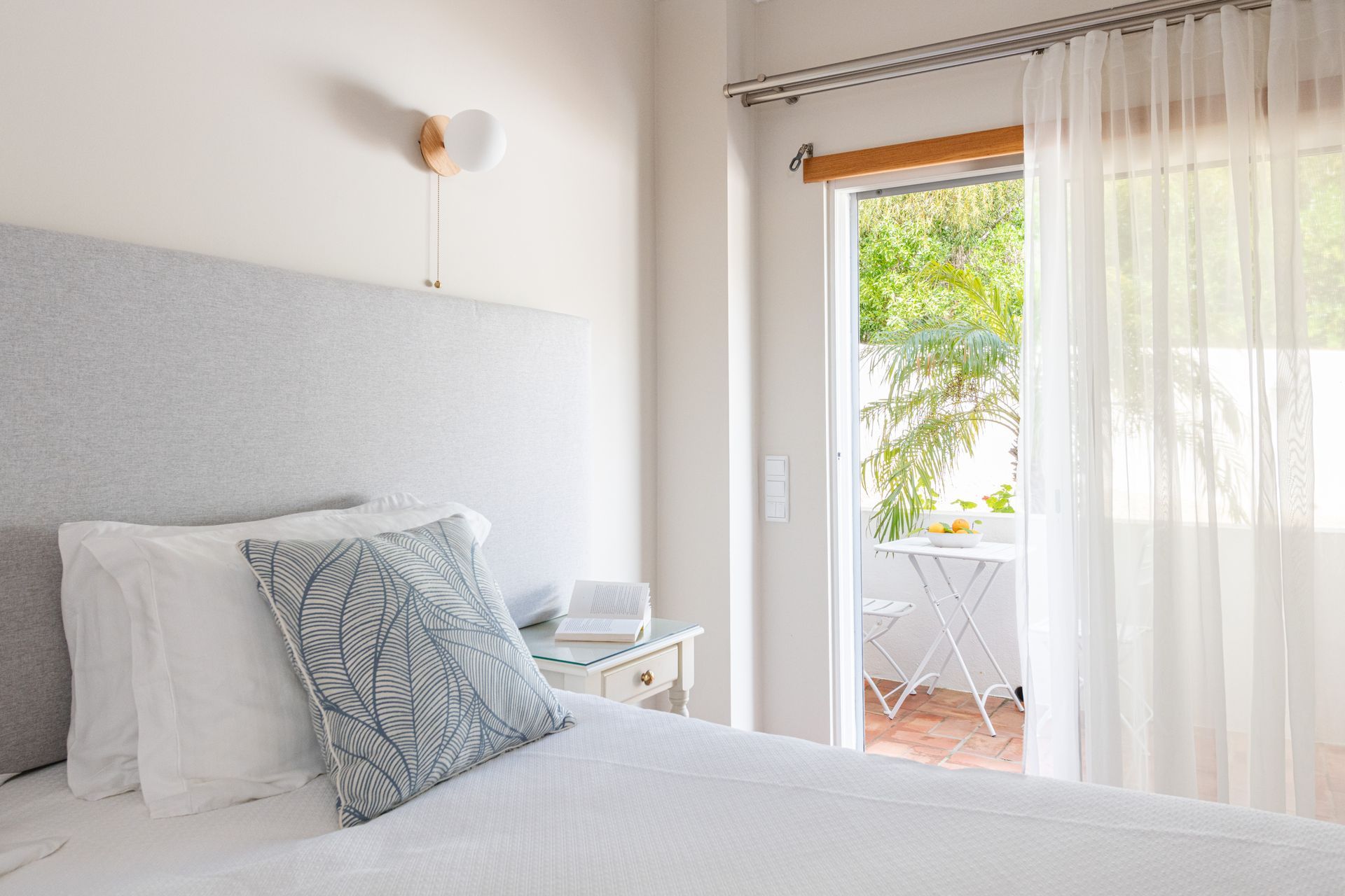 A bedroom with a bed and a sliding glass door leading to a balcony.
