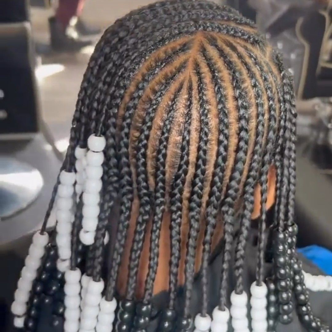 A back view of hair styled in straight cornrows adorned with black and white beads at the ends.