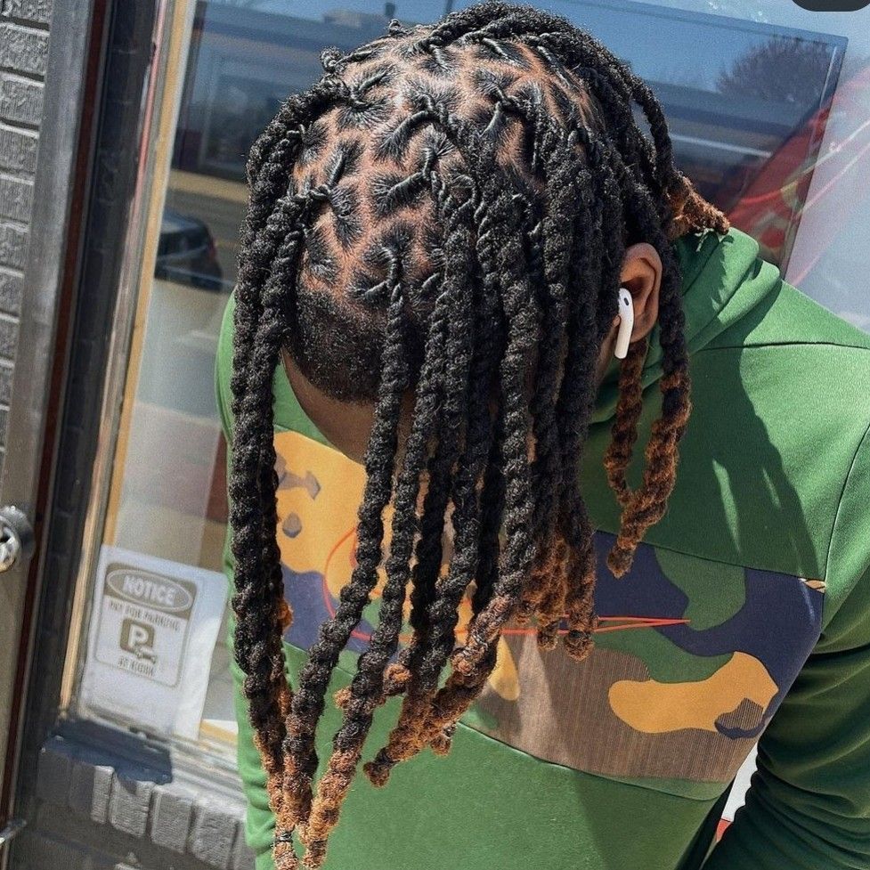 A person with shoulder-length, two-strand twists styled with a faded undercut, wearing a green camo print hoodie.