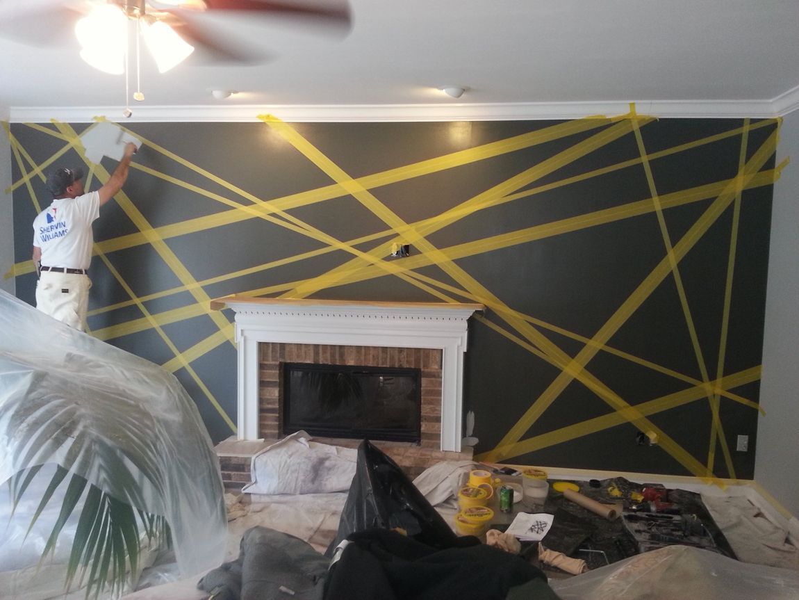 Living room with black wall, yellow tape lines, fireplace, and covered furniture during renovation