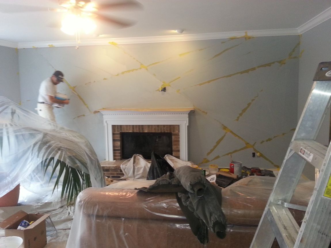 Living room being painted, with ladder, covered furniture, and a fireplace under renovation