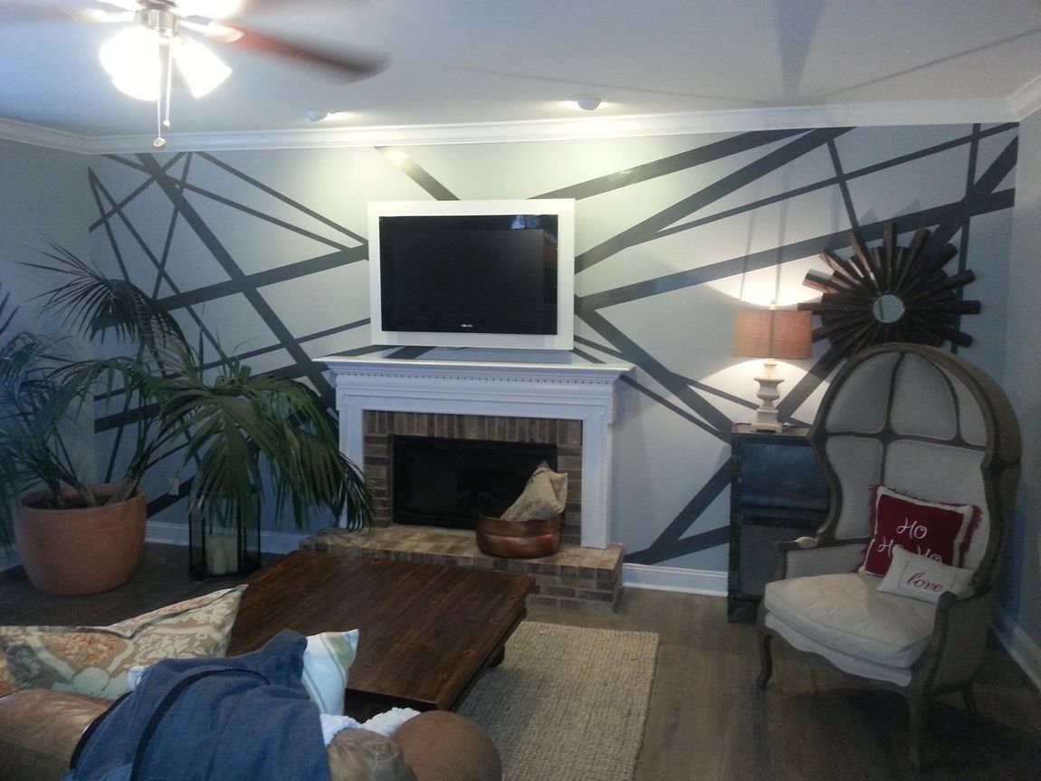 Living room with fireplace, TV, woven chair, coffee table, plants, and a cat by the hearth