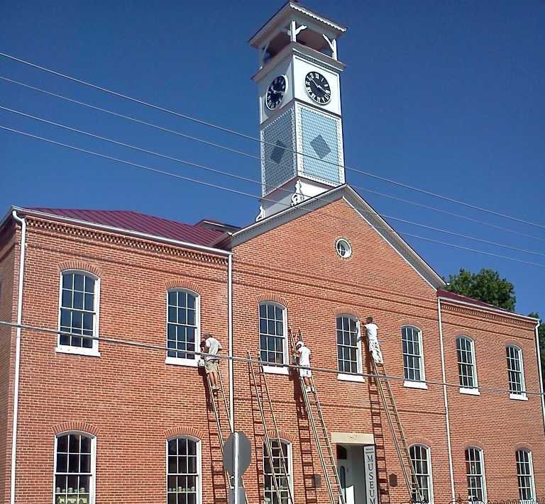 Red brick civic building with a white clock tower against a clear blue sky