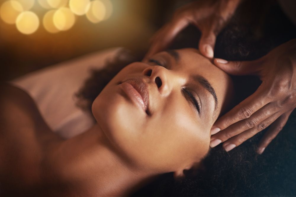Person receiving a facial massage with eyes closed in a dimly lit spa setting