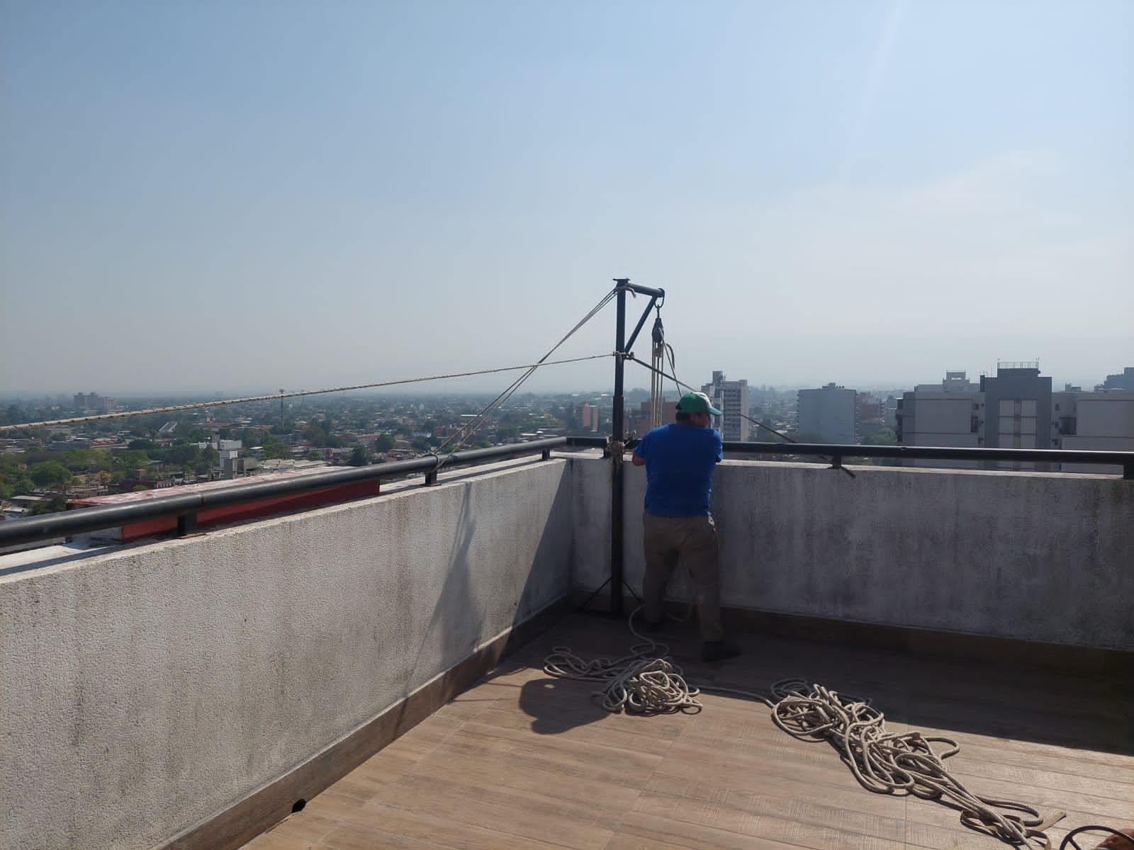 Persona en una azotea cerca de un equipo, con vistas a un paisaje urbano en un día soleado.