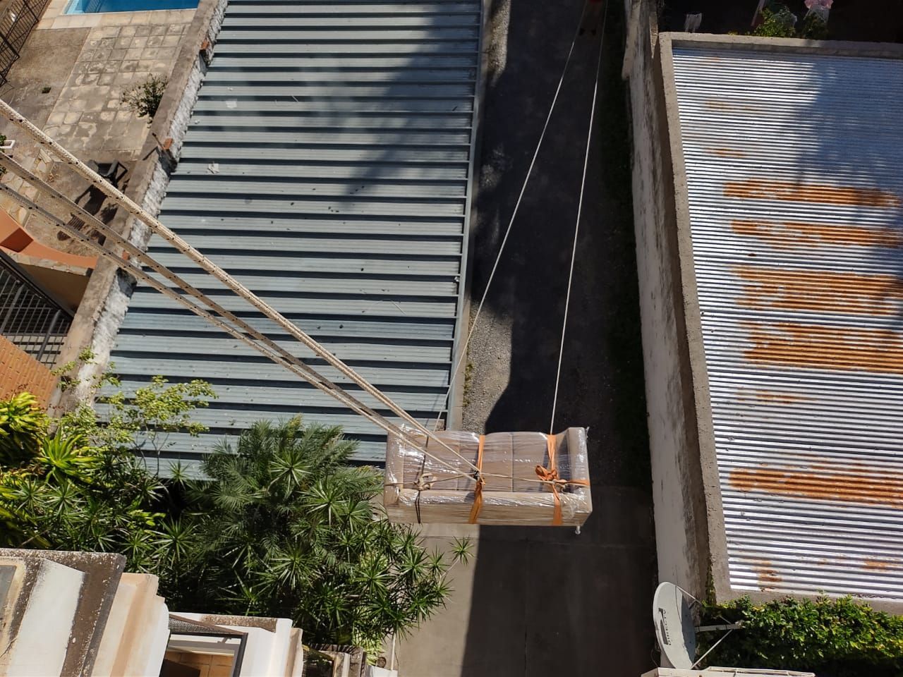 Vista aérea: Se levanta una caja de ladrillos con una cuerda desde un edificio. 