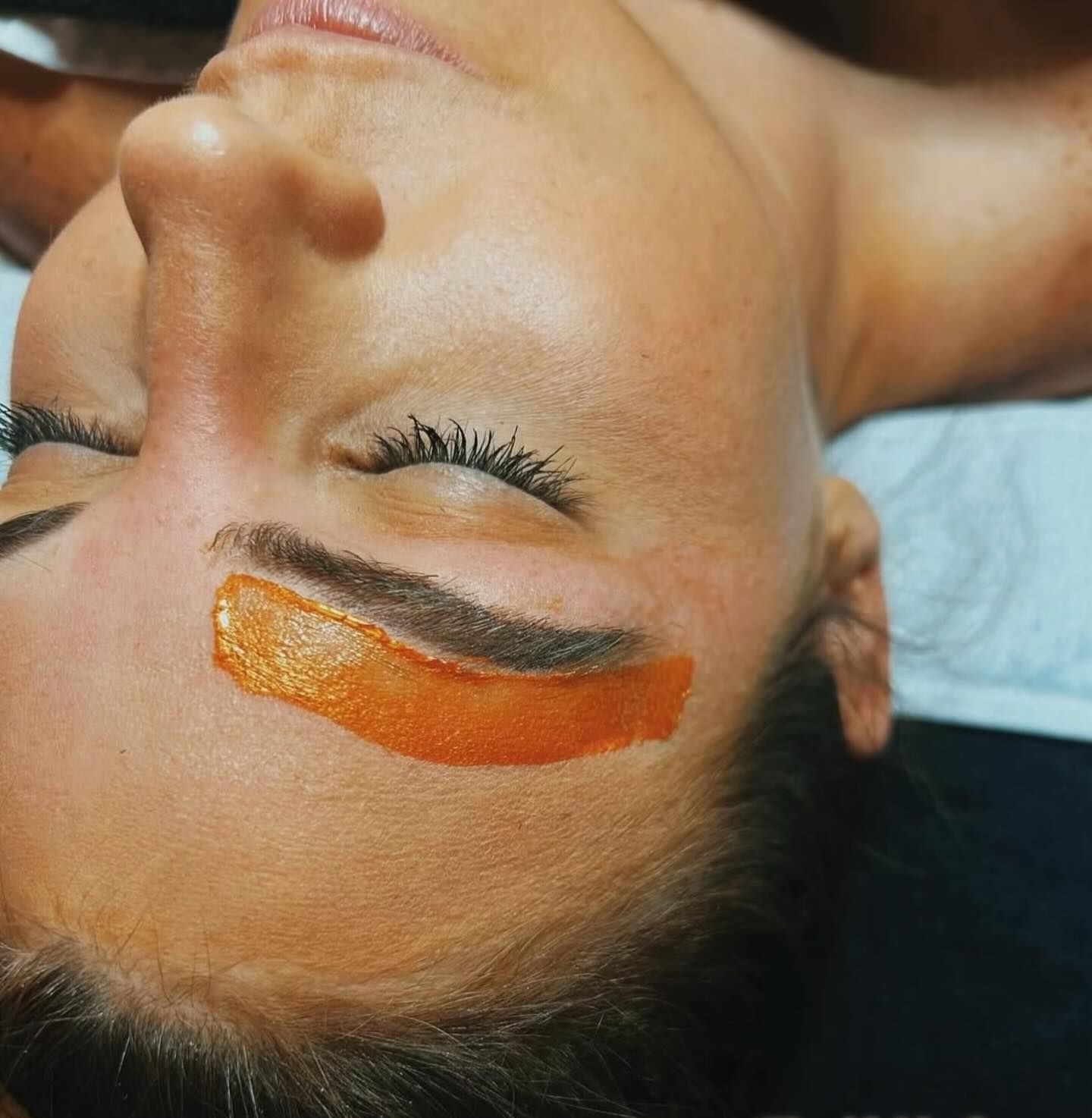 A close up of a woman 's face with orange paint on it