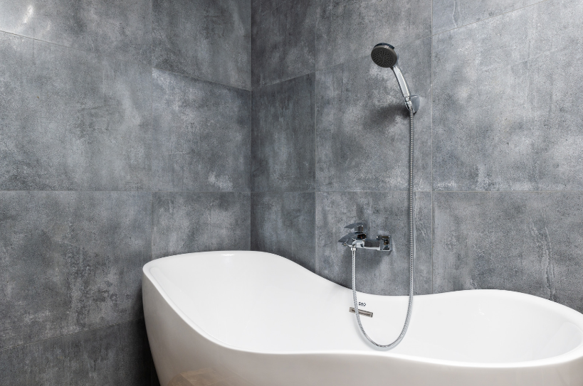 A white bathtub with a shower head attached to it in a bathroom.