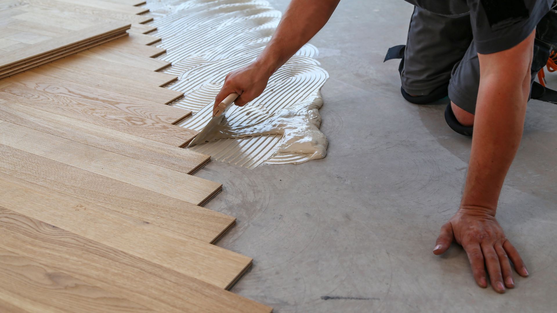A man is applying glue to a wooden floor.