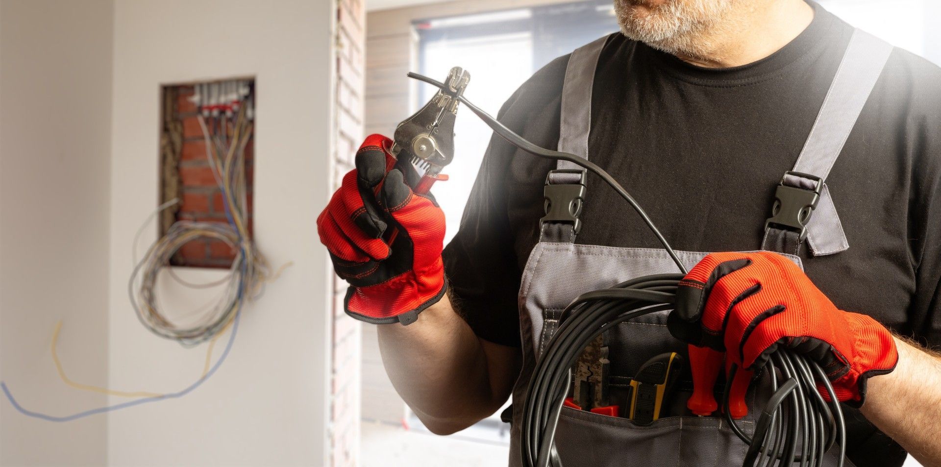 A man is holding a pair of pliers and a bunch of wires.
