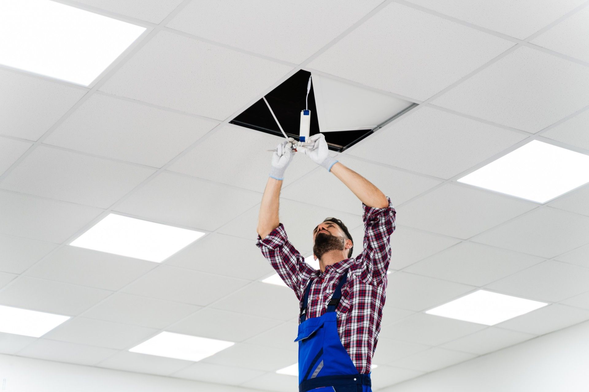 A man is fixing a light fixture on the ceiling.
