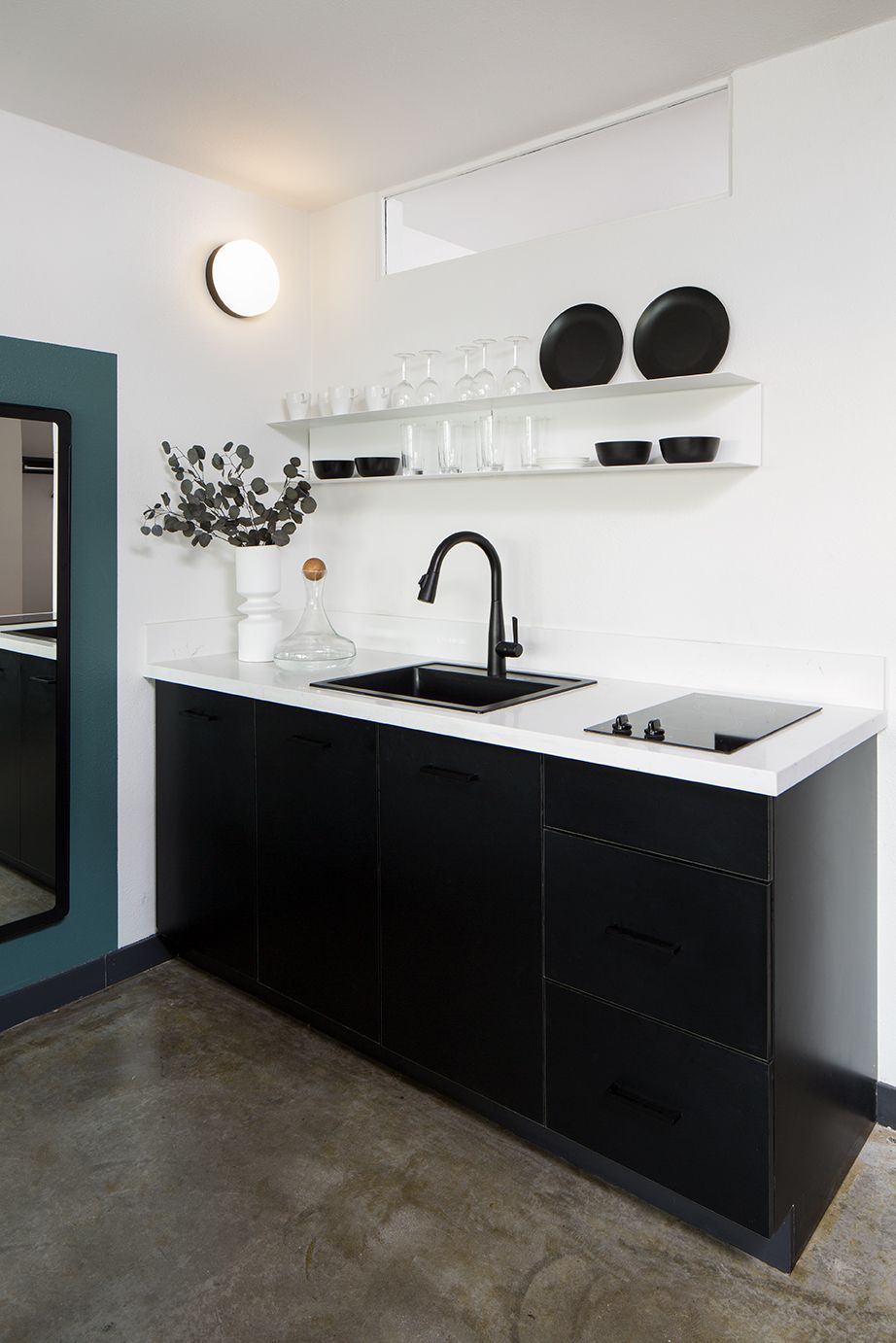 Modern black-and-white kitchenette with sink, shelf decor, and compact appliances