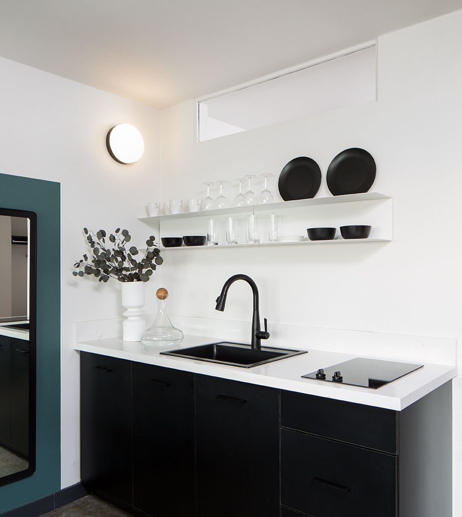 Modern studio apartment with bed, desk, wall-mounted TV, and large window with city view