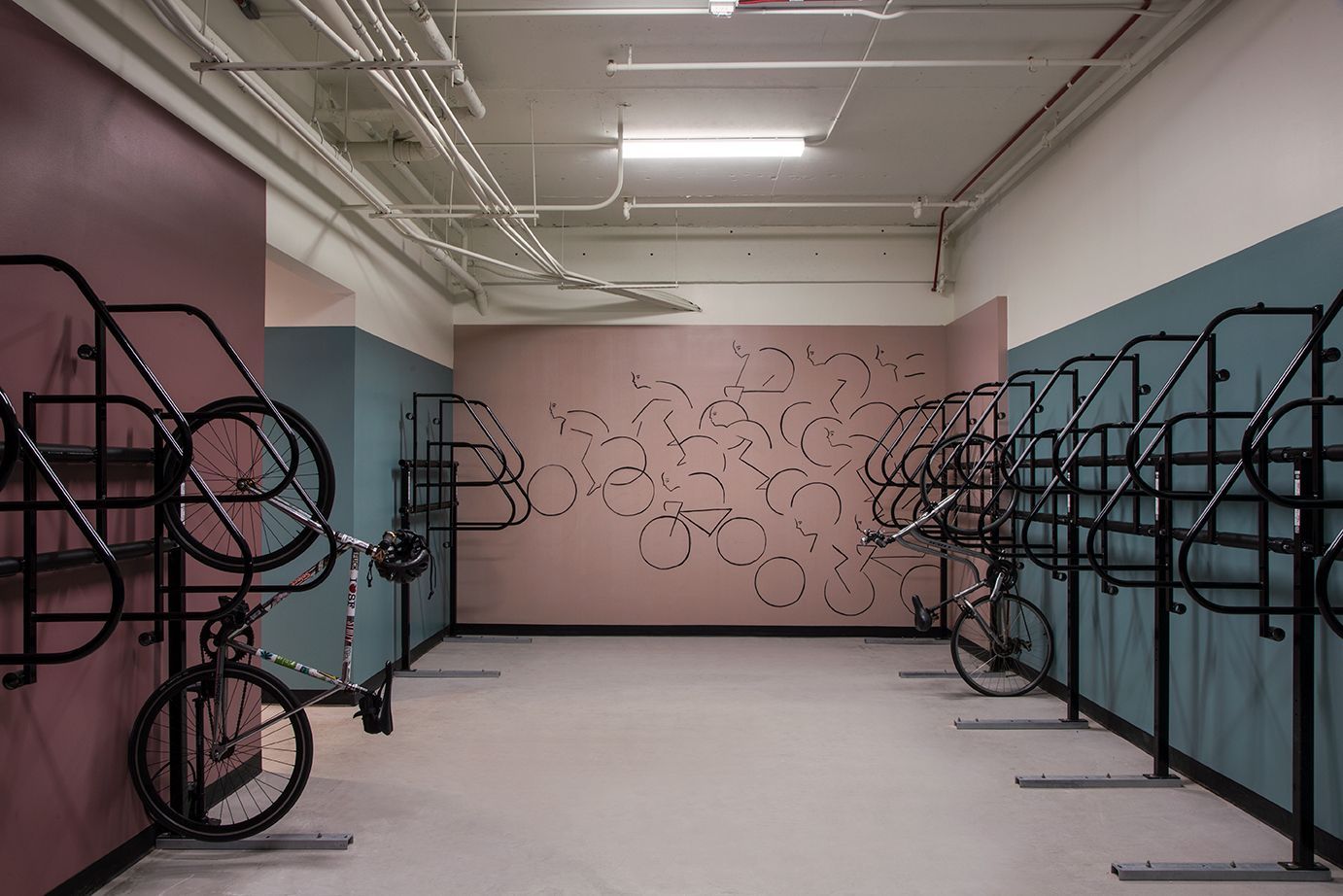 Empty art gallery with white floor, pink back wall, and black metal sculpture frames along both sides