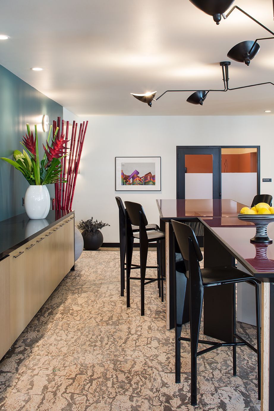 Modern living room with bar stools, patterned rug, and red flowers in a vase