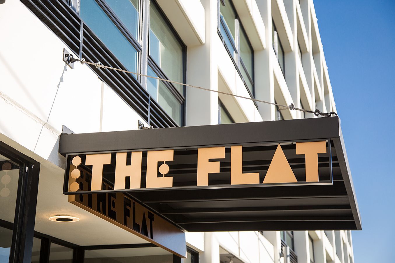Sign reading “THE FLAT” on a modern building awning