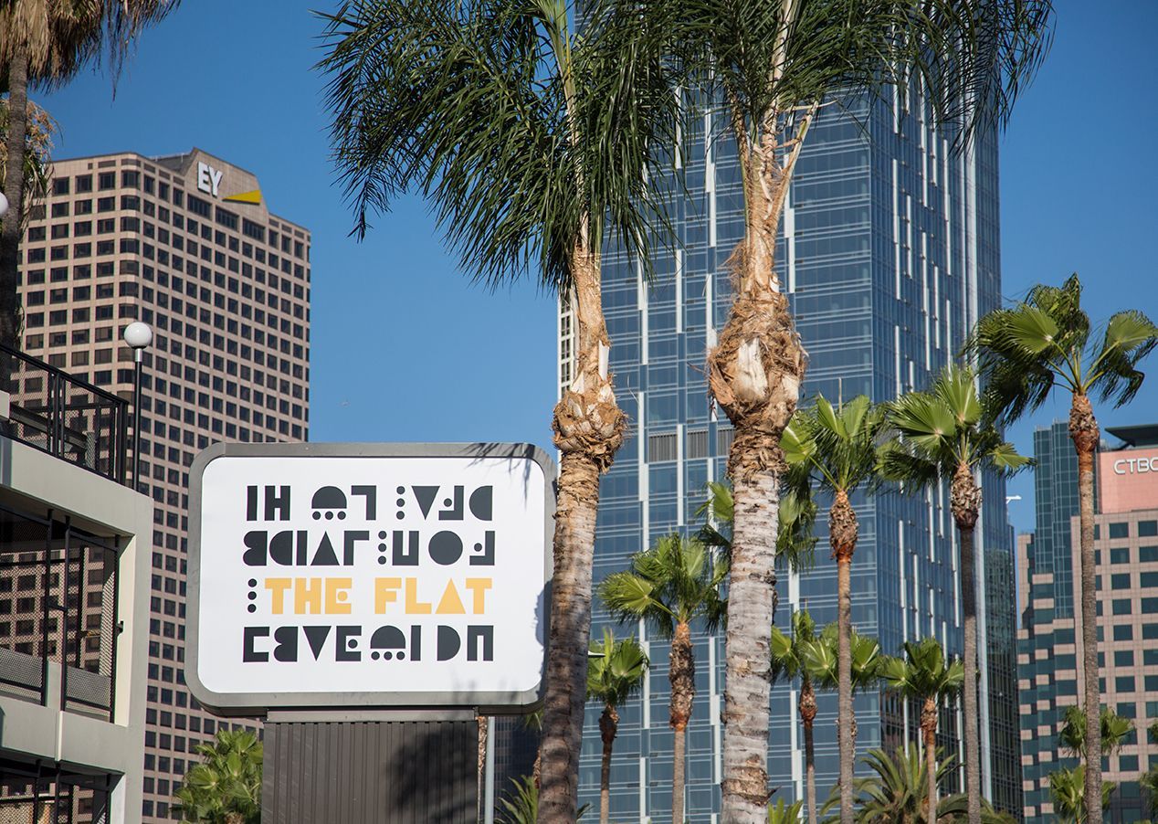 Downtown street with palm trees, high-rises, and a mirrored sign with reversed text.